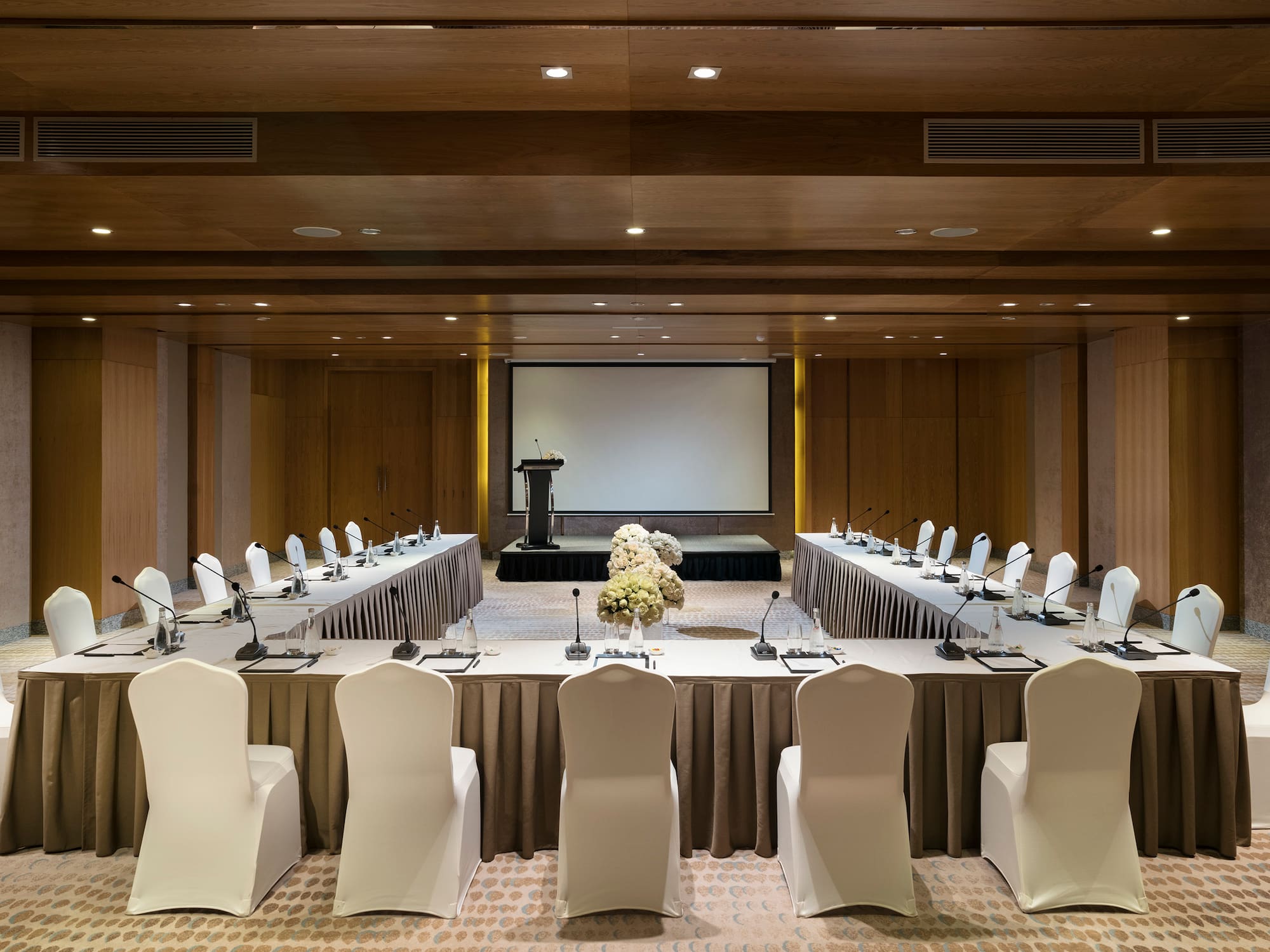 a room with a large table with chairs and a projector screen