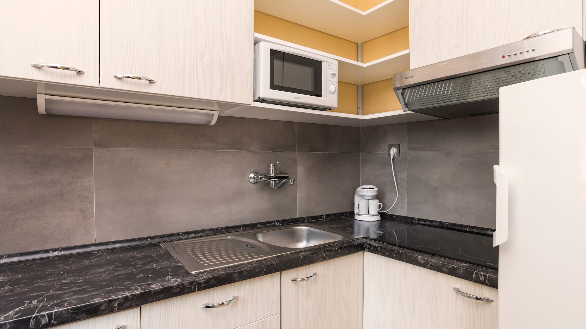 a kitchen with white cabinets and black counter tops