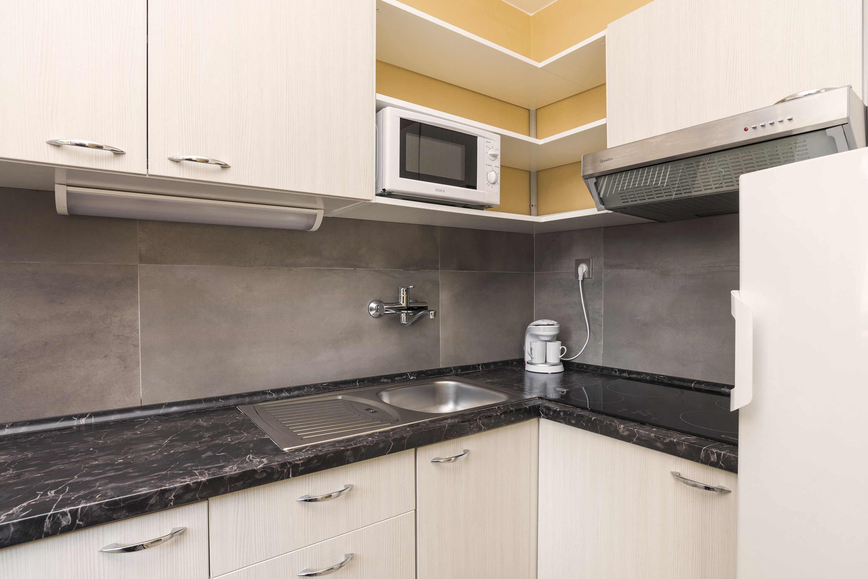 a kitchen with white cabinets and black counter tops