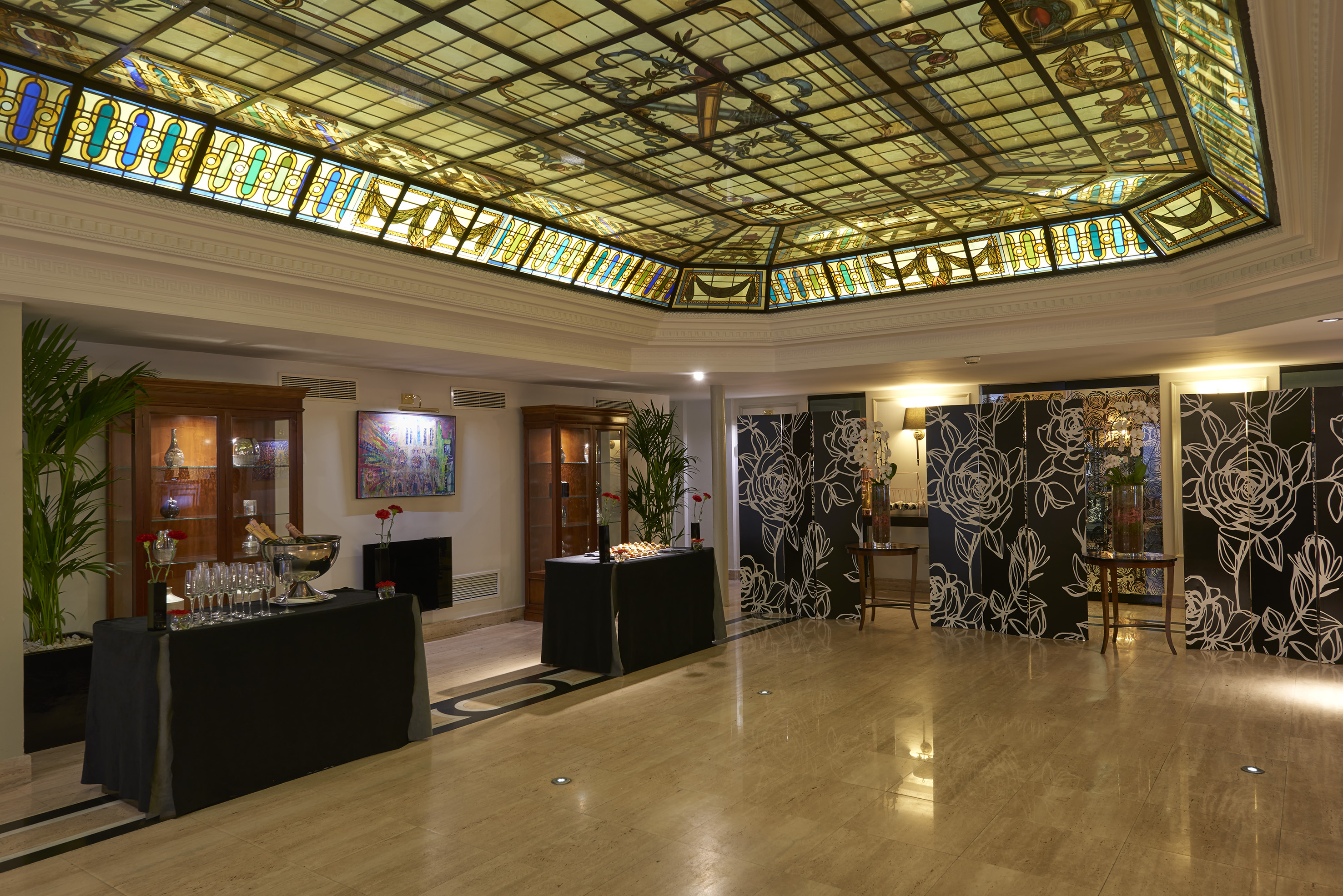 Stunning stained glass ceiling in an elegant hotel reception hall with bar.