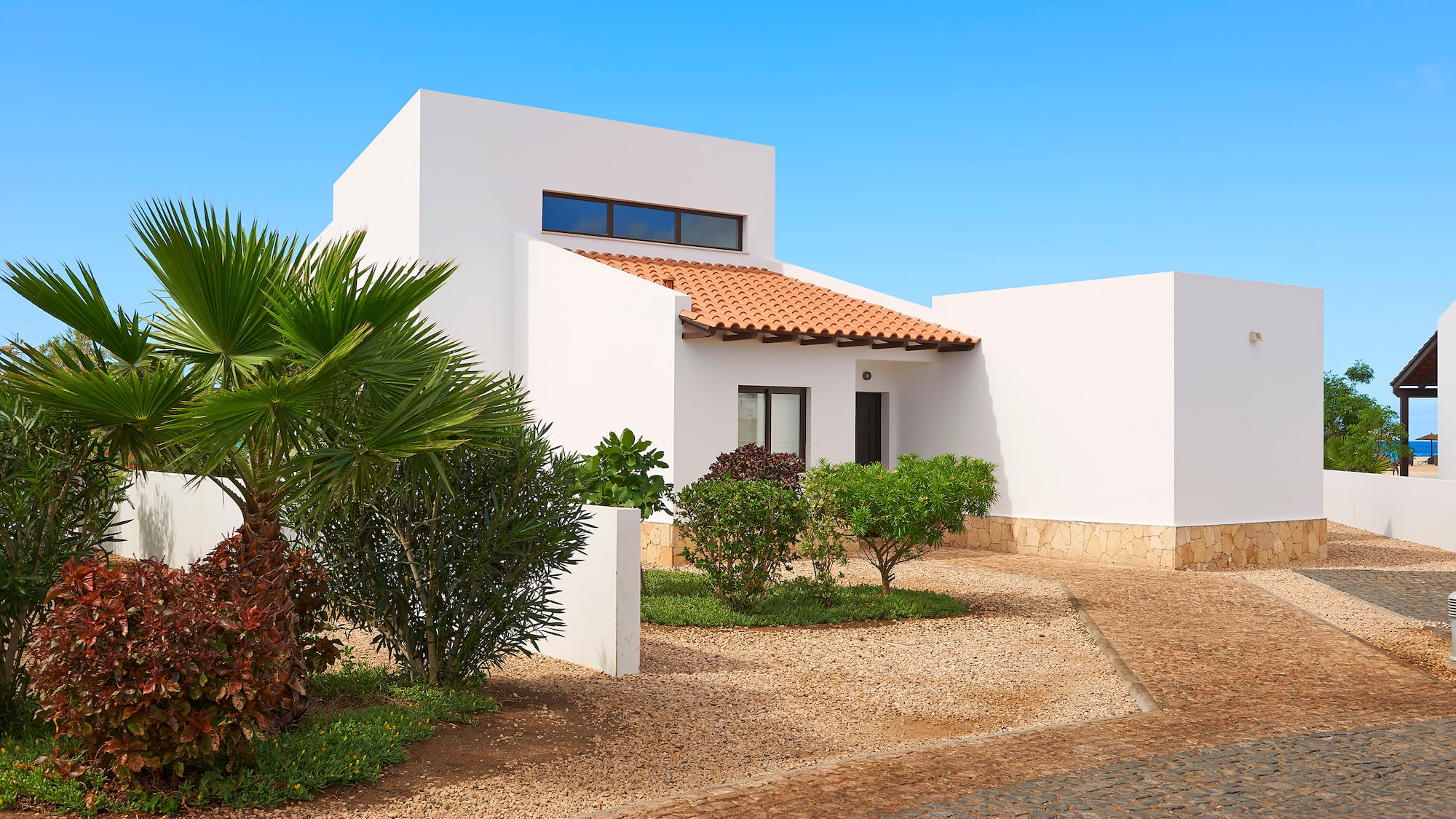a white house with a driveway and bushes