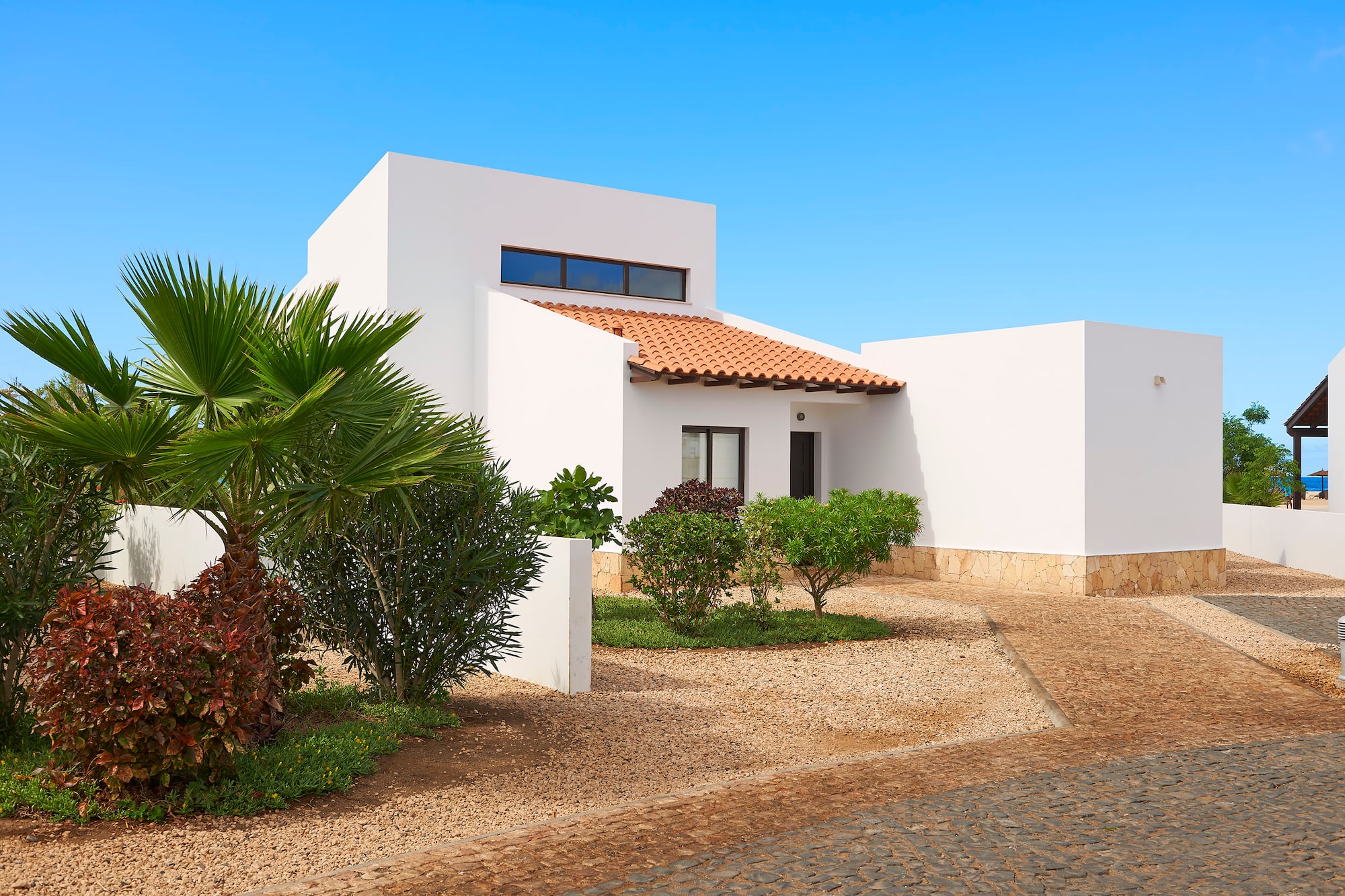 a white house with a driveway and bushes