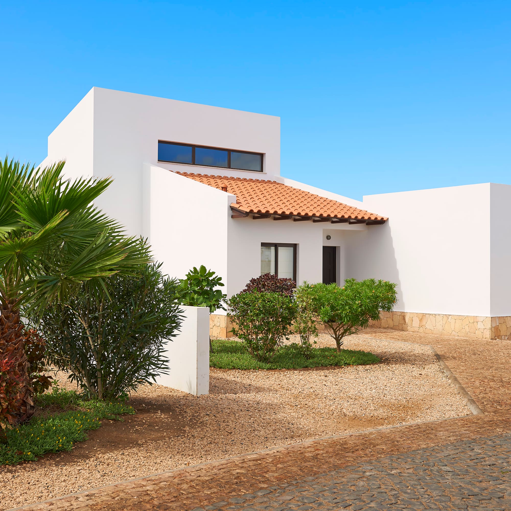 a white house with a driveway and bushes