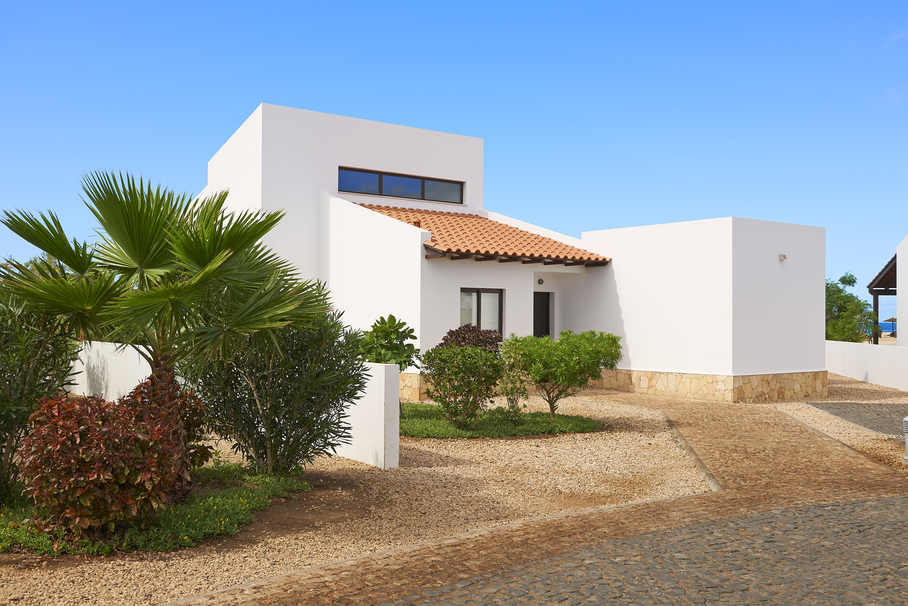 a white house with a driveway and bushes