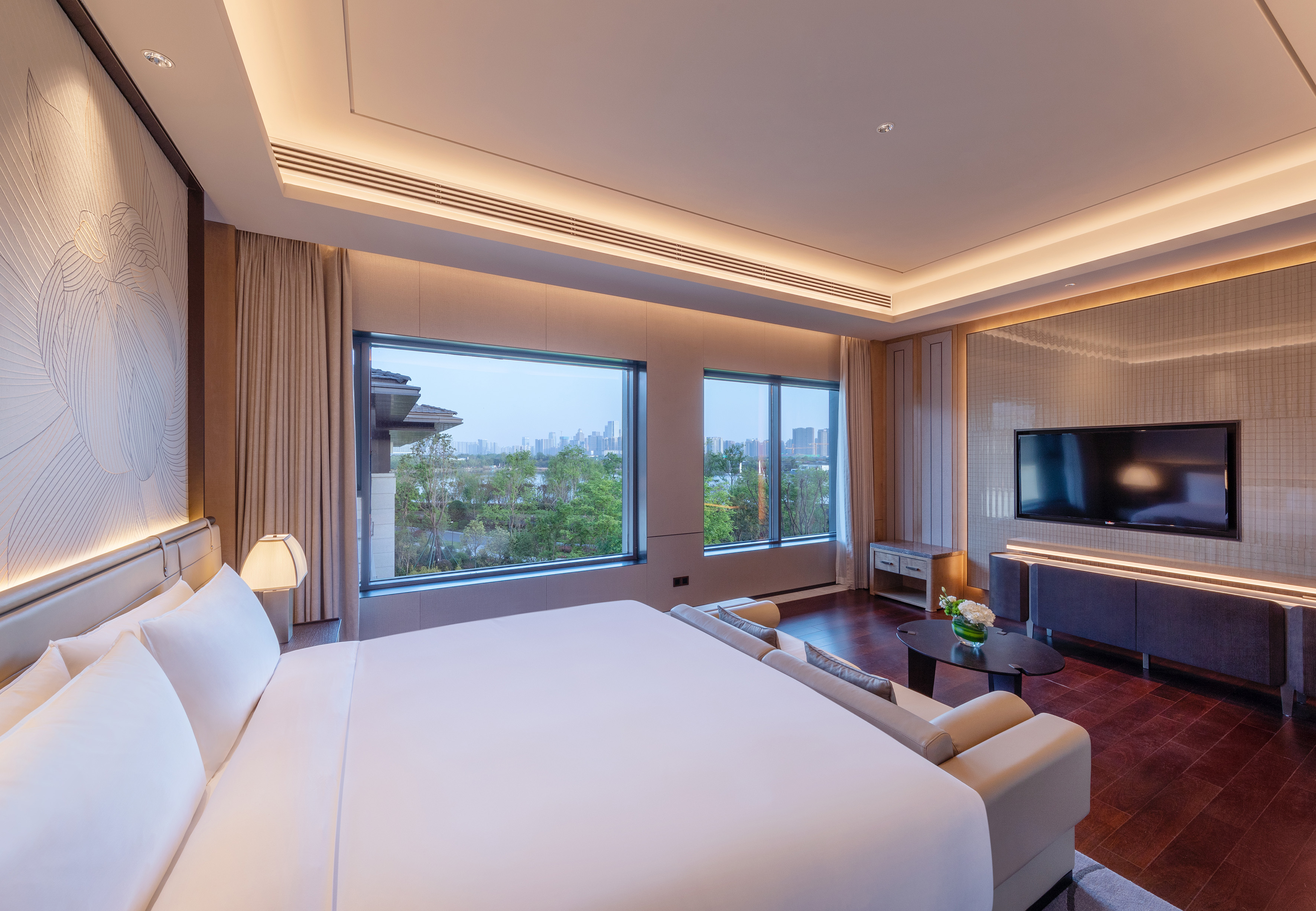 Luxury hotel suite with king bed, panoramic city view, and modern interior design.