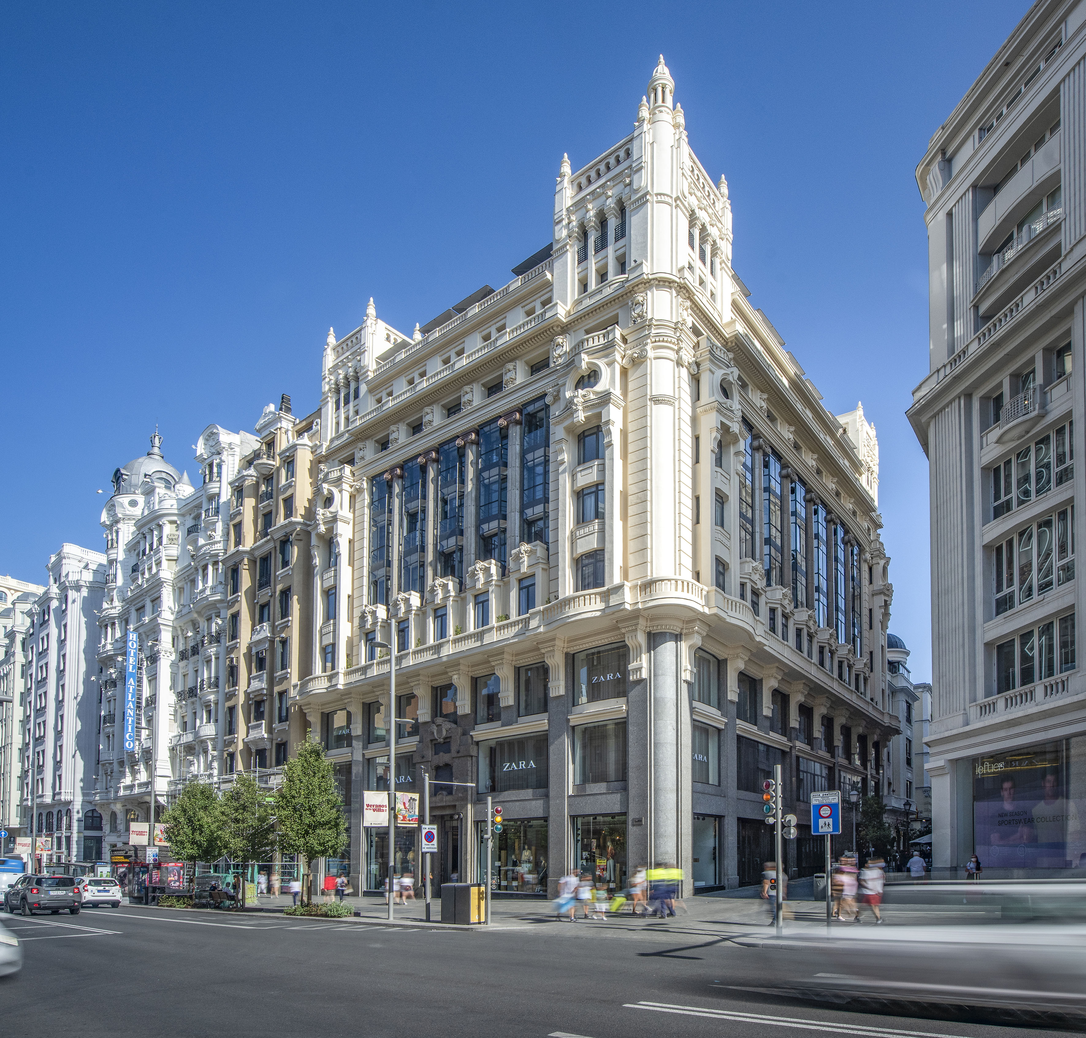 a street with a large building and people walking on it