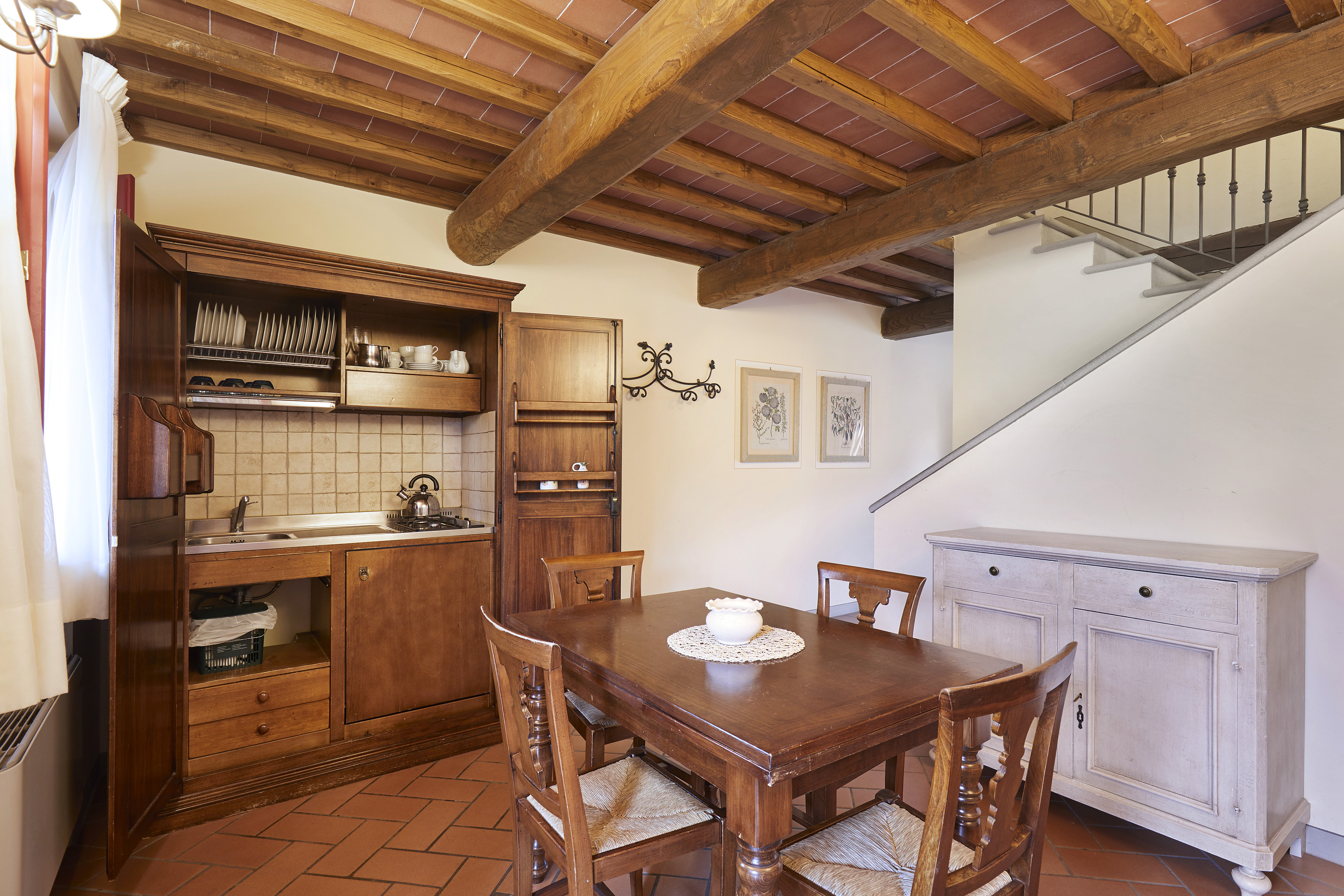 Rustic kitchen dining room, wood beams, terracotta floor, built-in hutch.