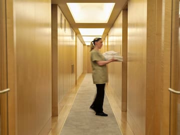 a woman carrying a towel in a hallway