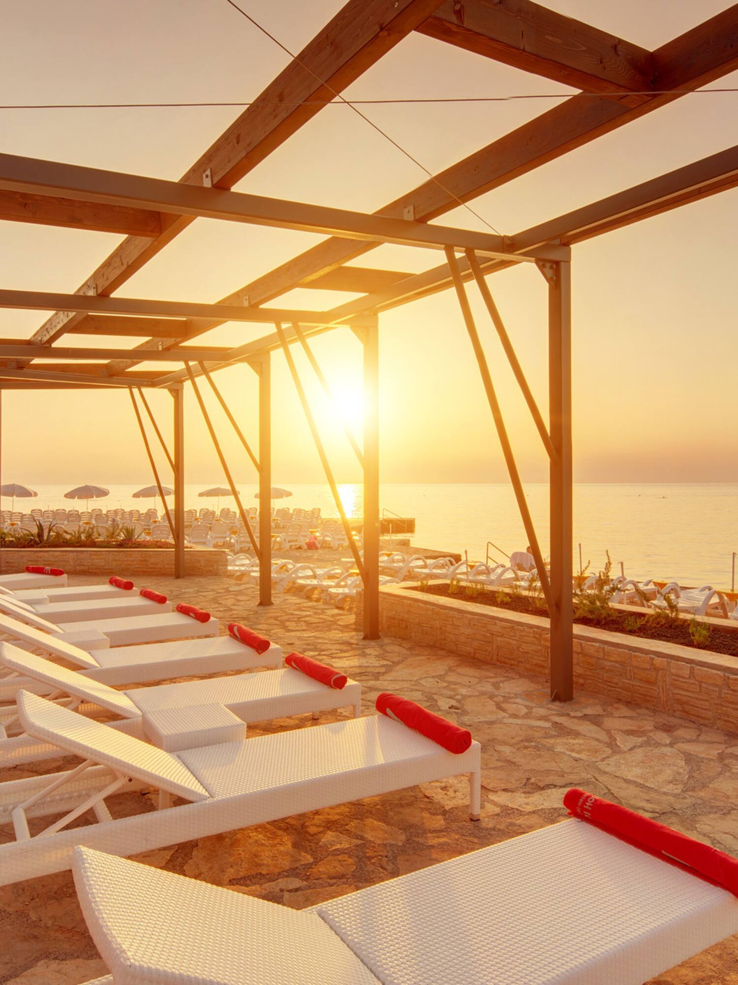 a sun set on a deck with lounge chairs