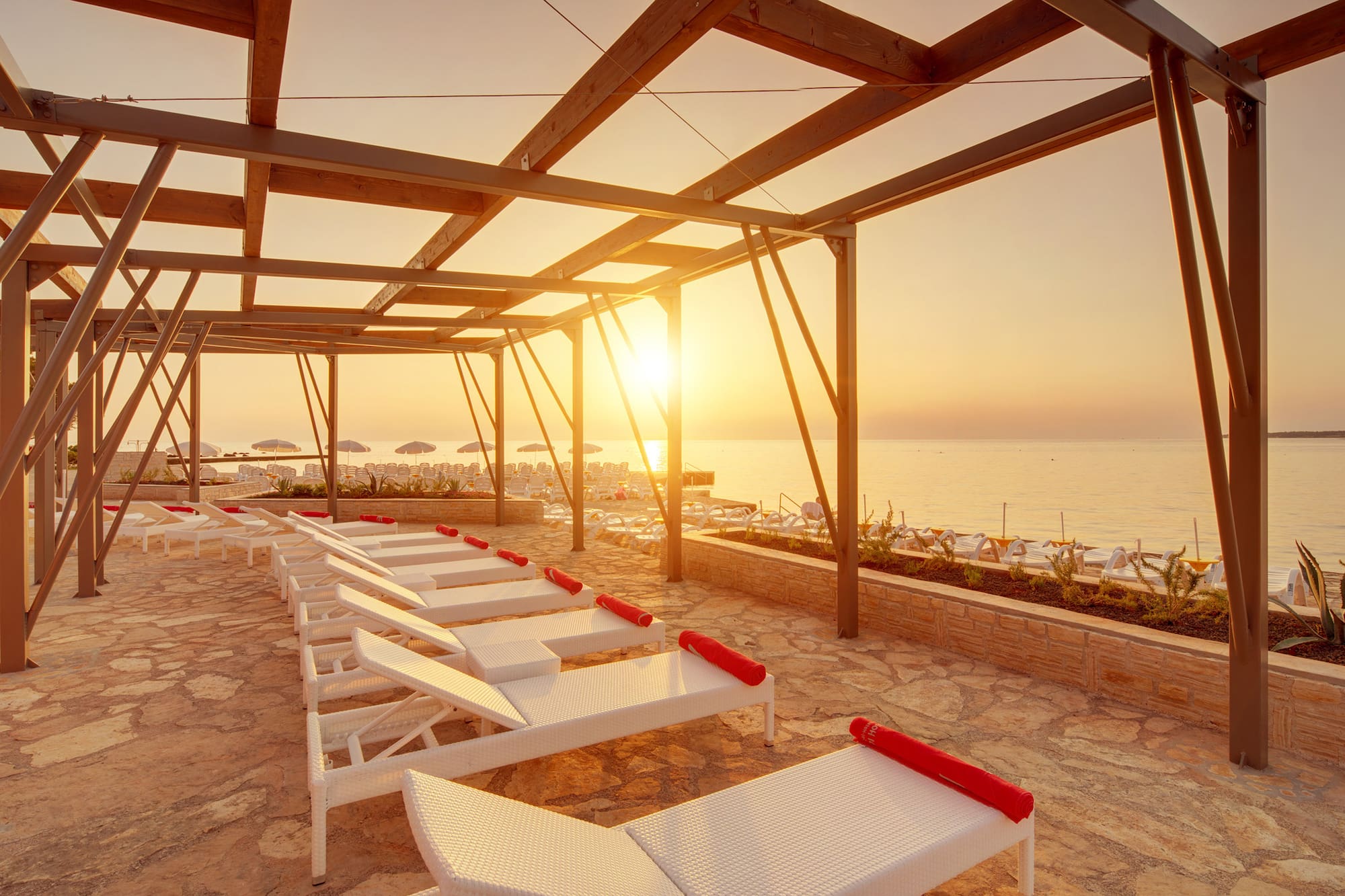 a sun set on a deck with lounge chairs