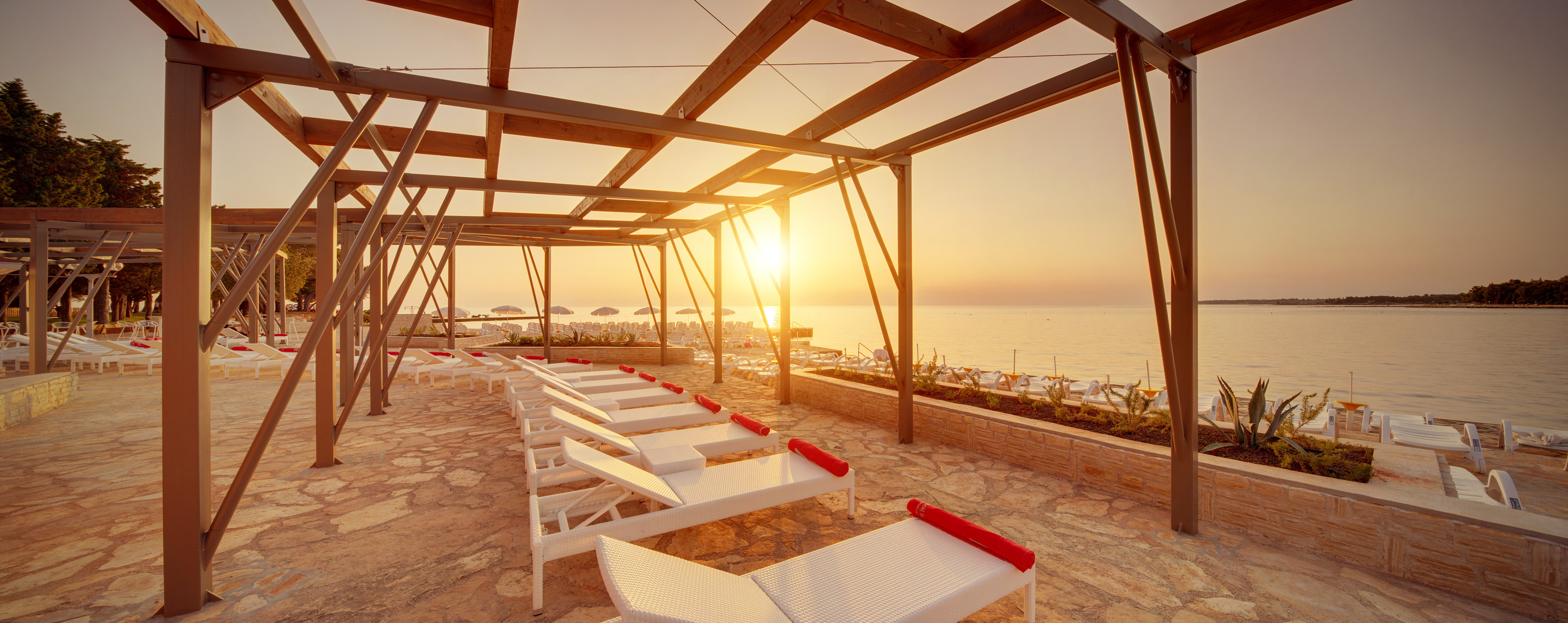 a sun set on a deck with lounge chairs