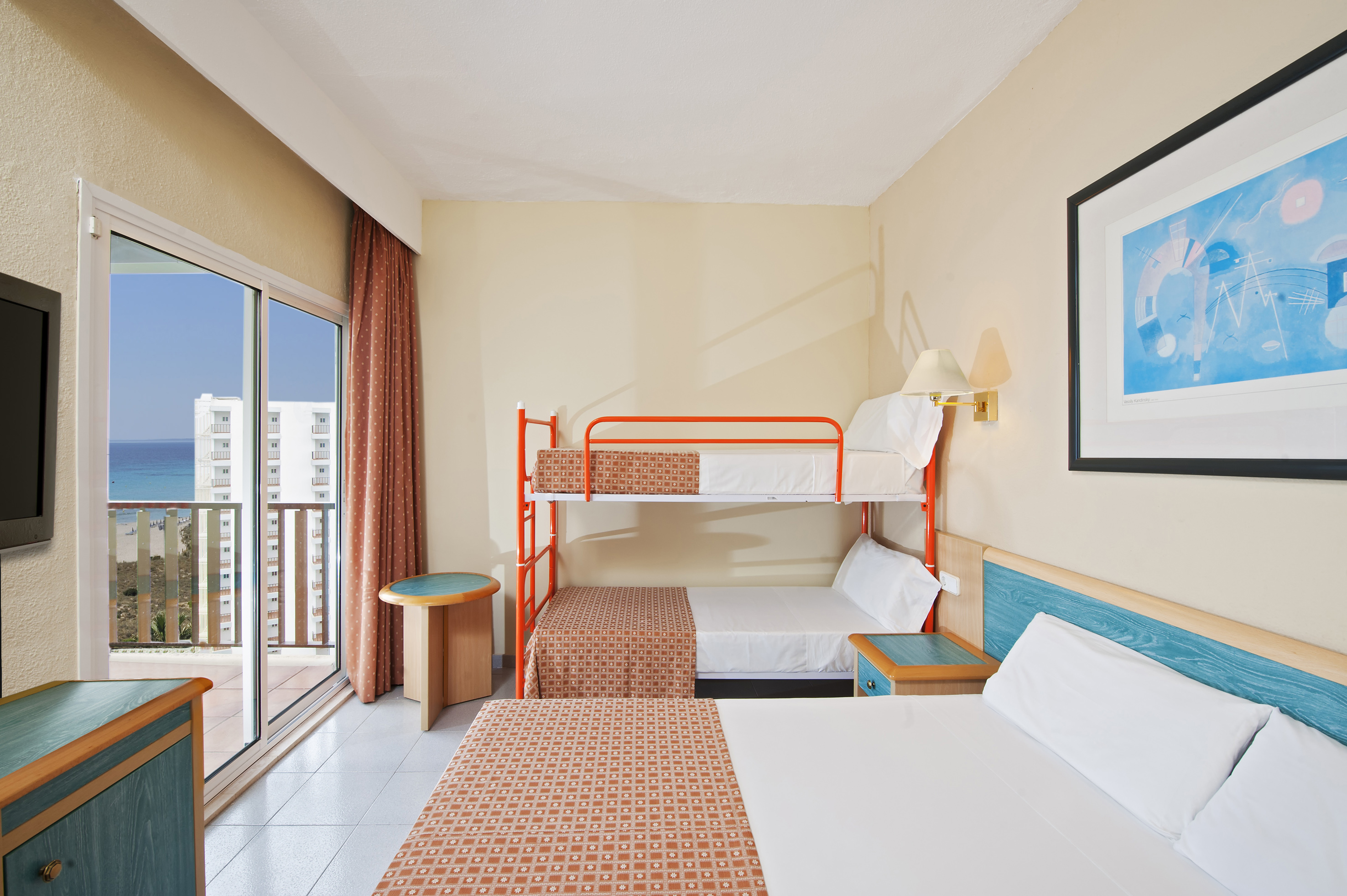 Hotel family room with double bed, bunk beds, and ocean view balcony.