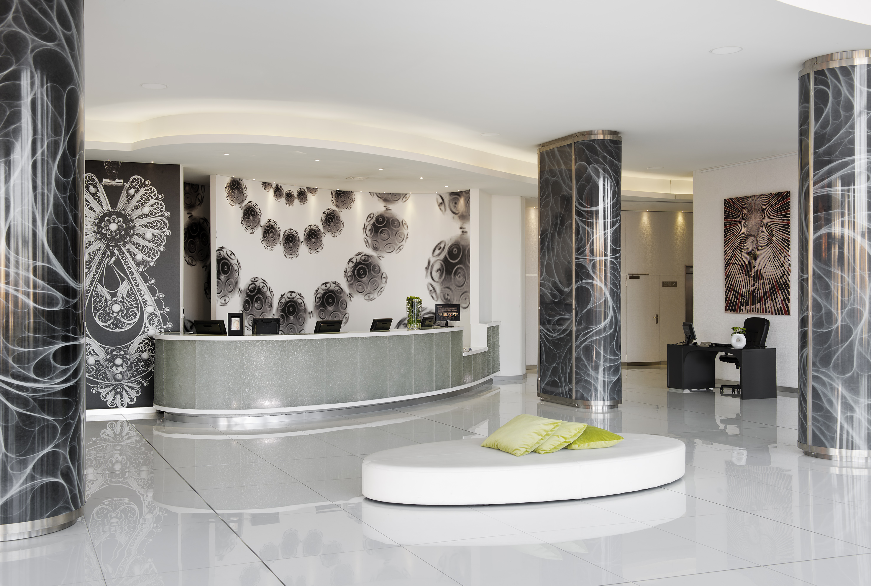Stylish hotel reception area with curved desk, abstract wall art, and lounge.