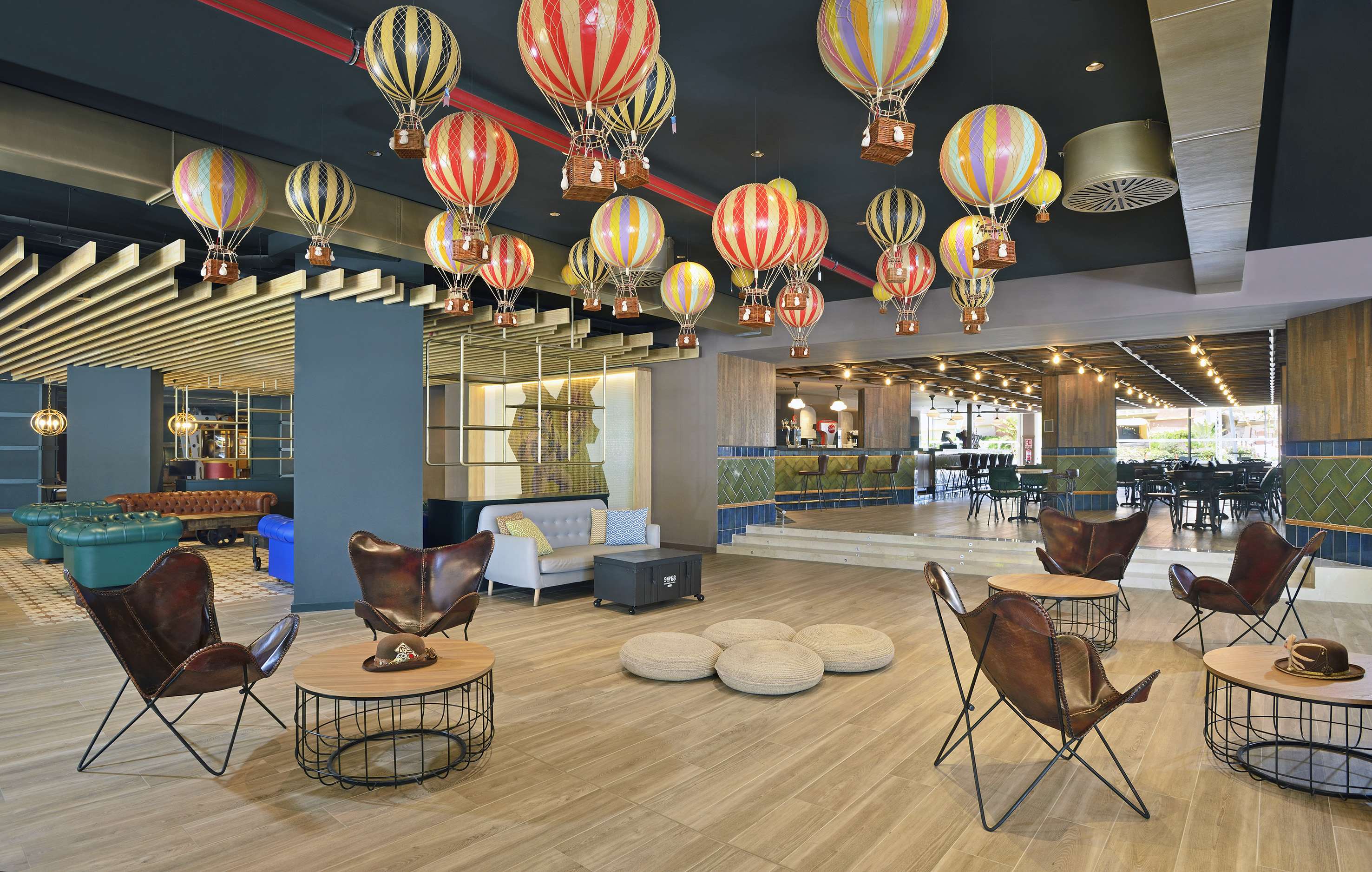 Modern hotel lobby lounge with colorful hot air balloons and eclectic seating.