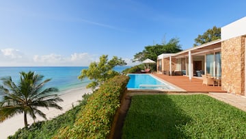 a pool and a house with a beach and trees