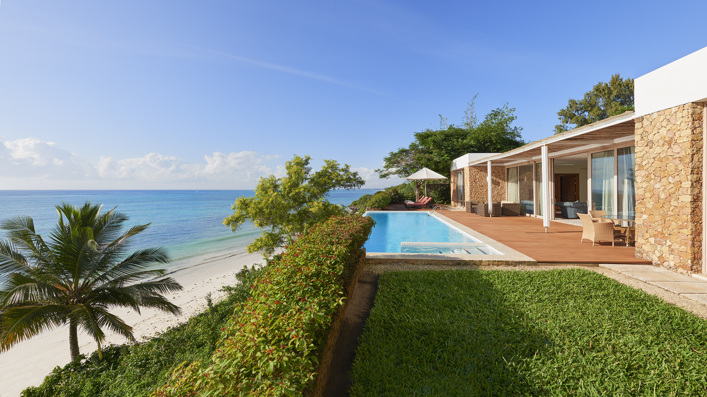 Beachfront luxury villa with private pool, stone walls, and turquoise ocean.