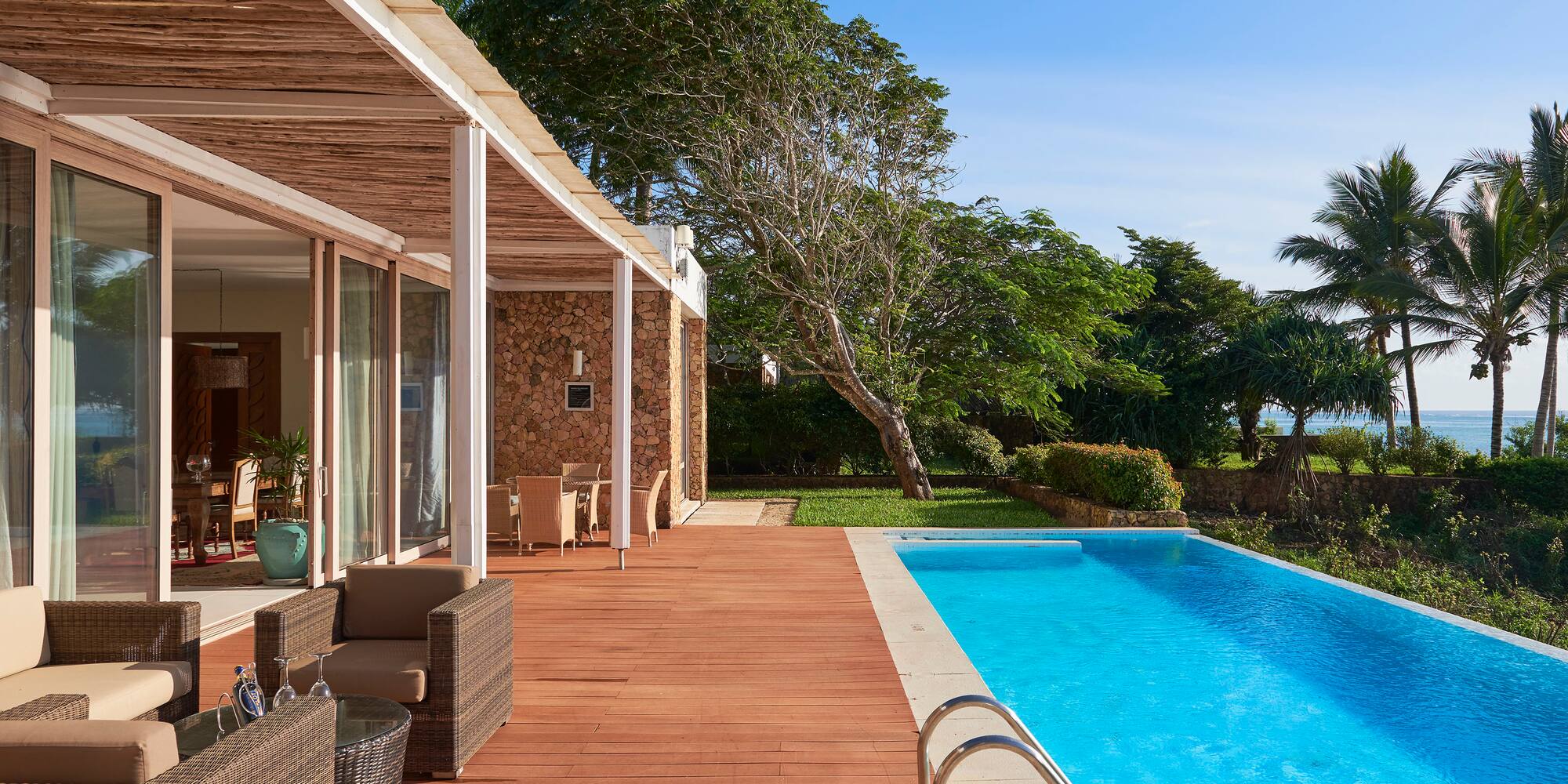 a swimming pool with a deck and a house with trees and a blue sky