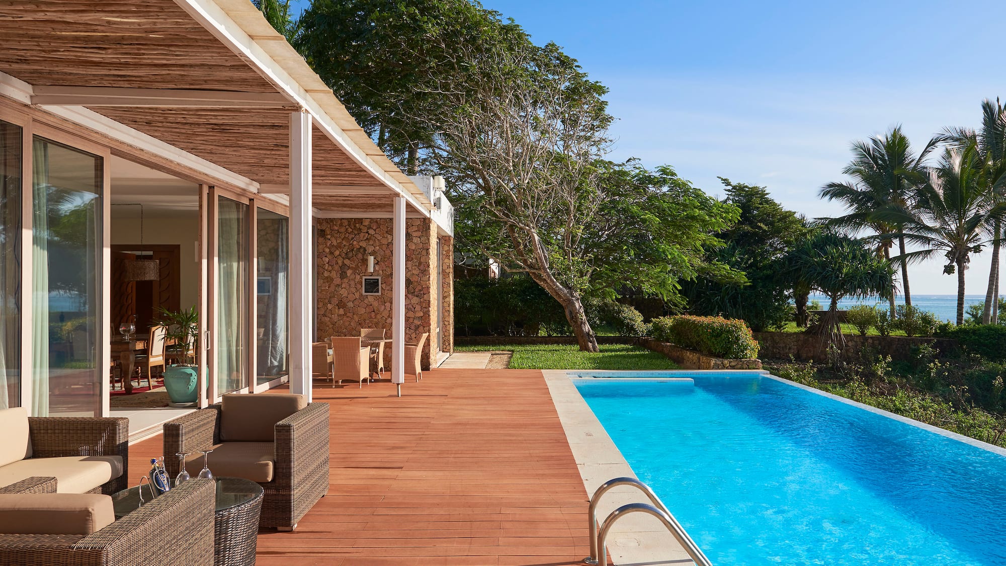 a swimming pool with a deck and a house with trees and a blue sky