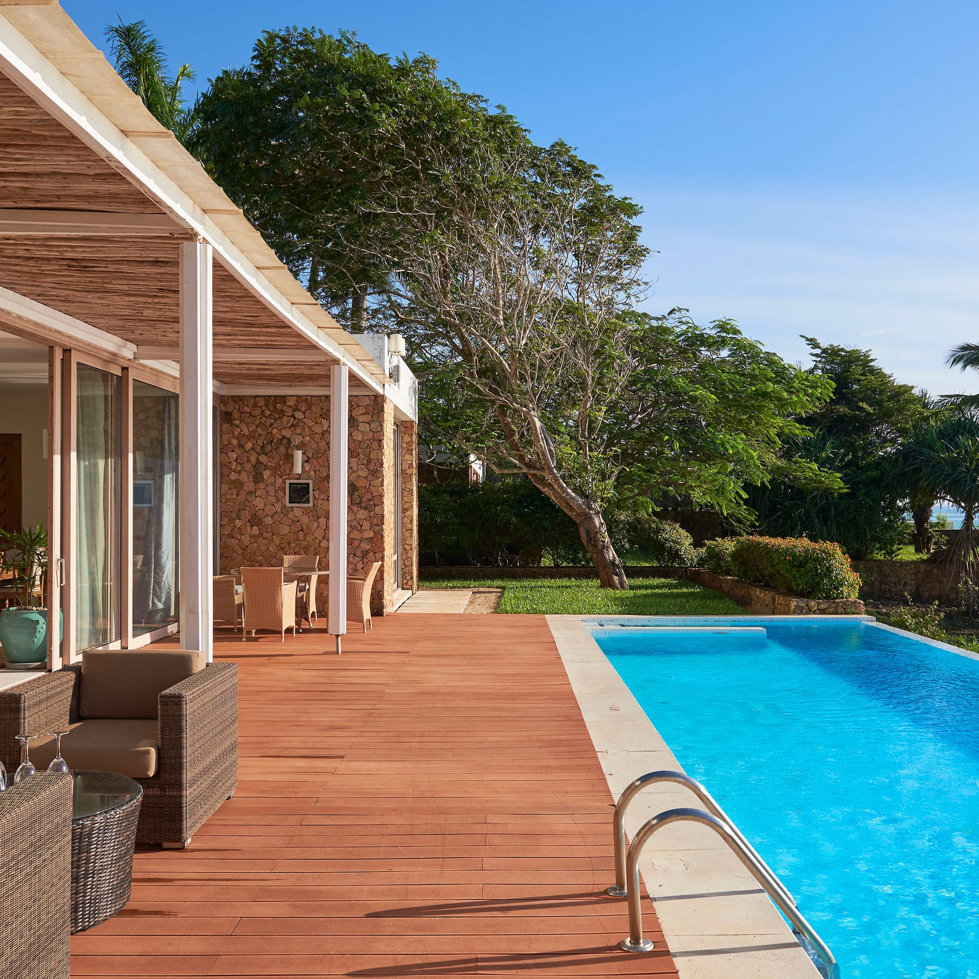 a swimming pool with a deck and a house with trees and a blue sky