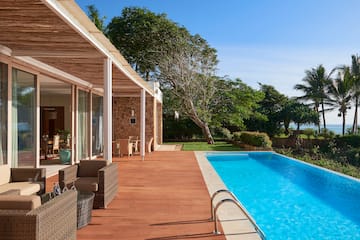 a swimming pool with a deck and a house with trees and a blue sky