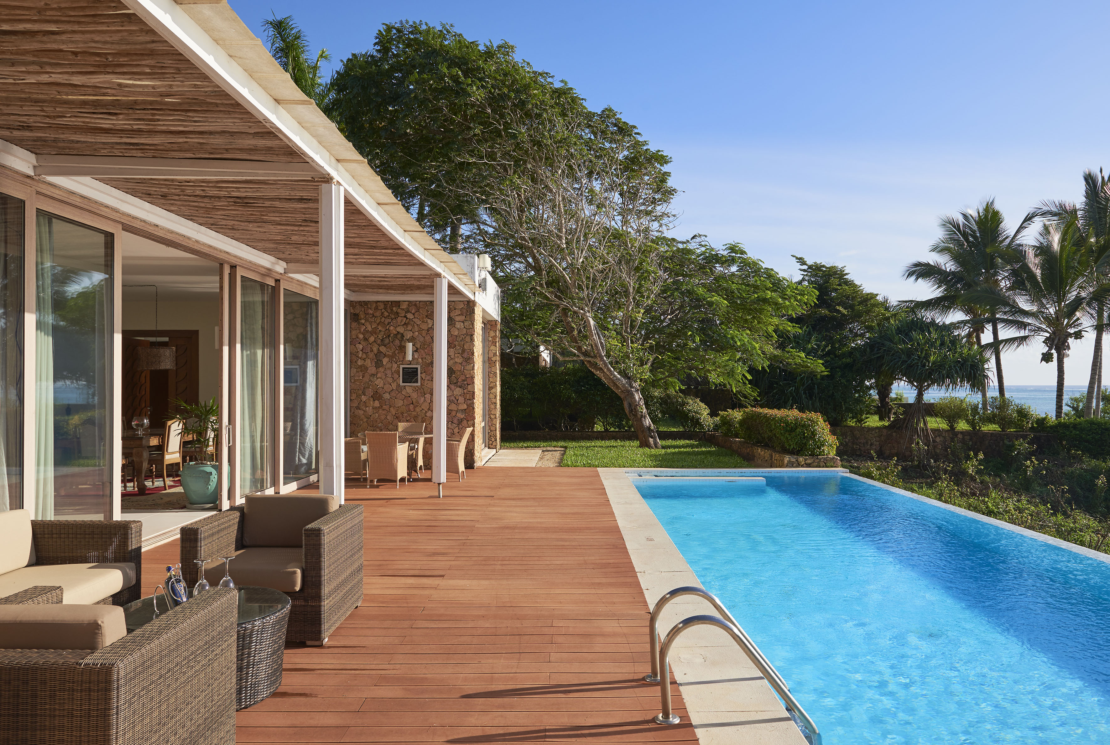 a swimming pool with a deck and a house with trees and a blue sky