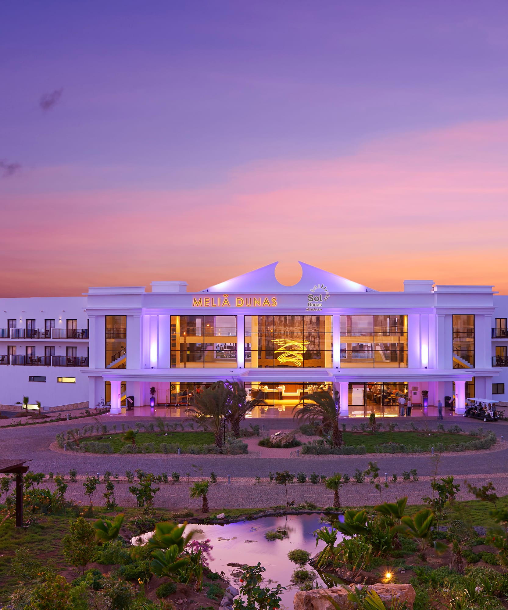 a building with a pond and trees in front