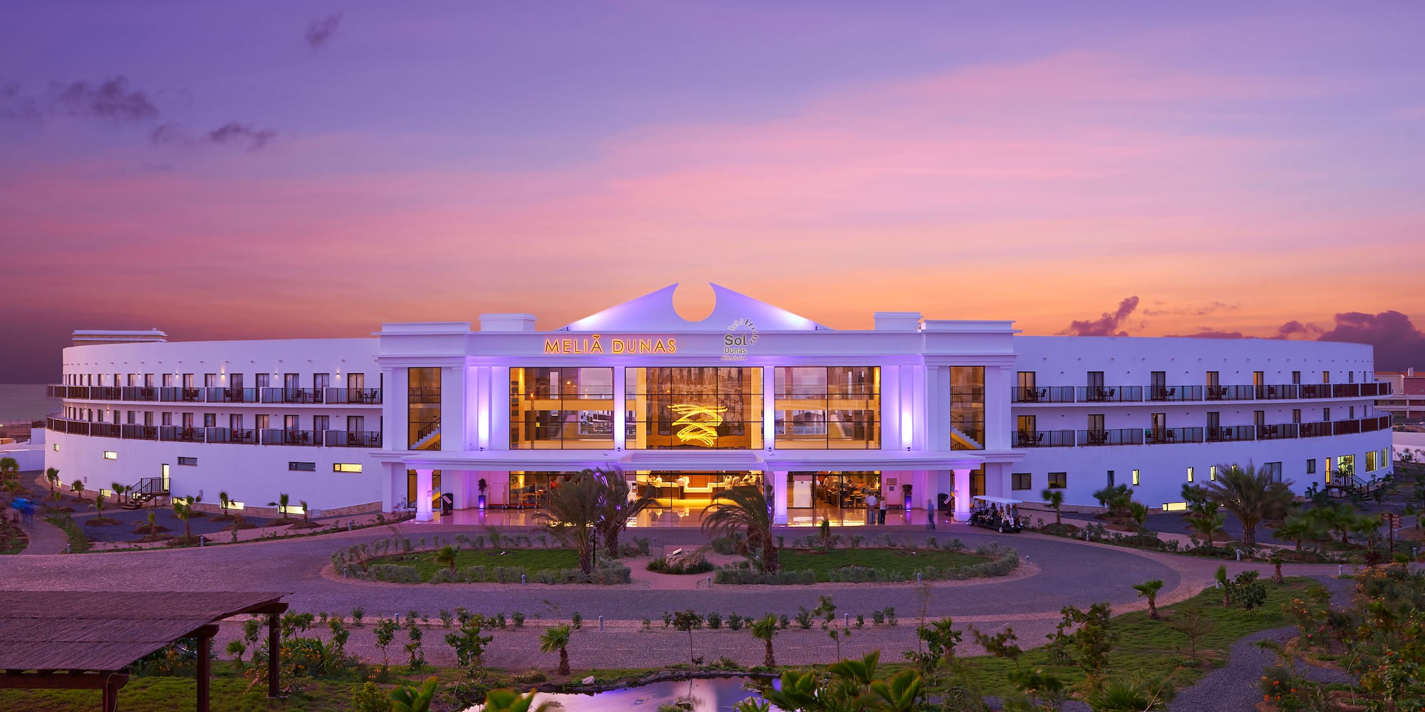 a building with a pond and trees in front