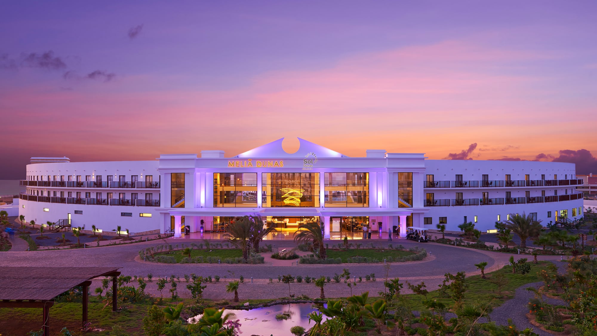 a building with a pond and trees in front