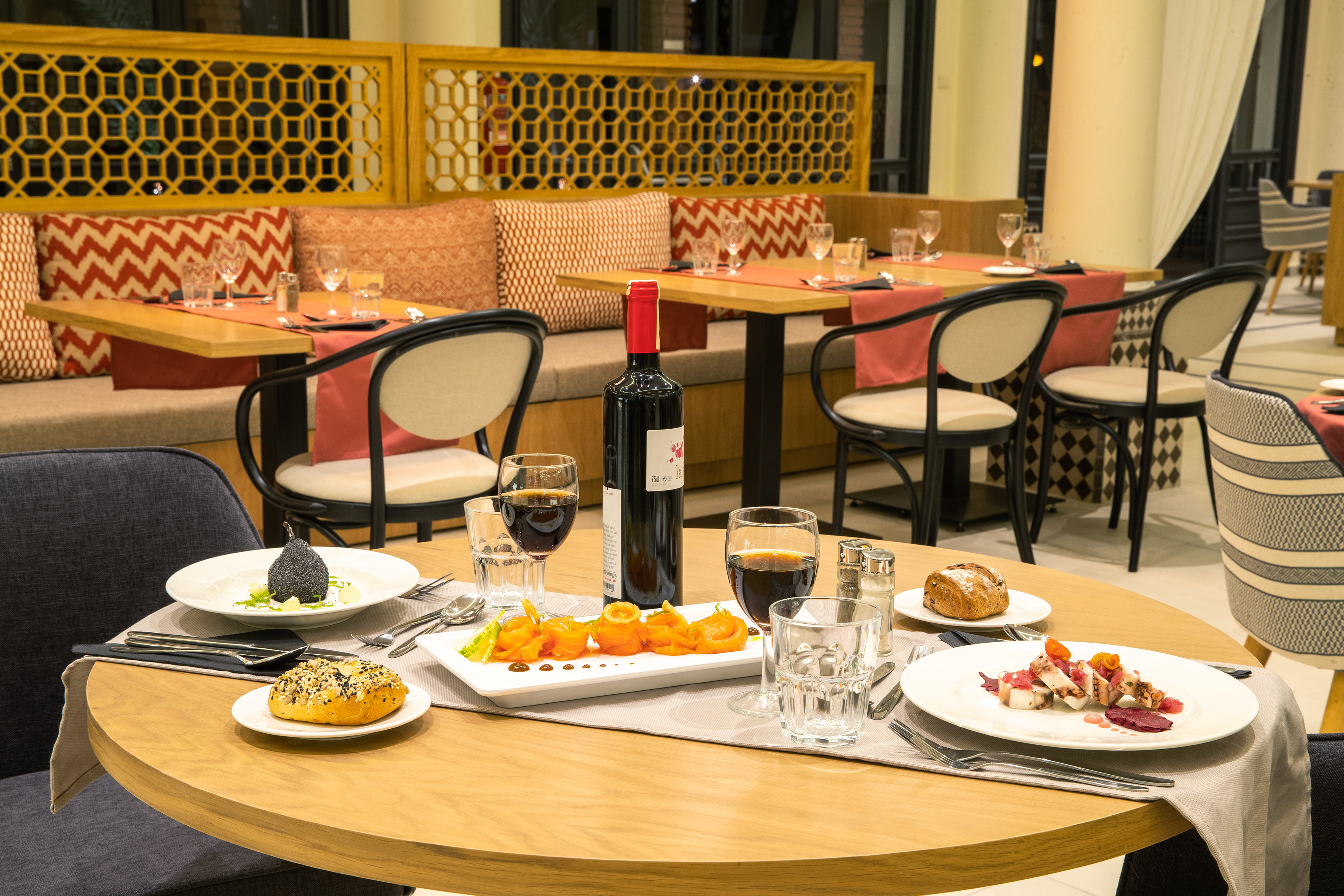Restaurant dining table set with wine, prepared food, and elegant decor.