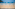 a white fence with a beach and boats in the background