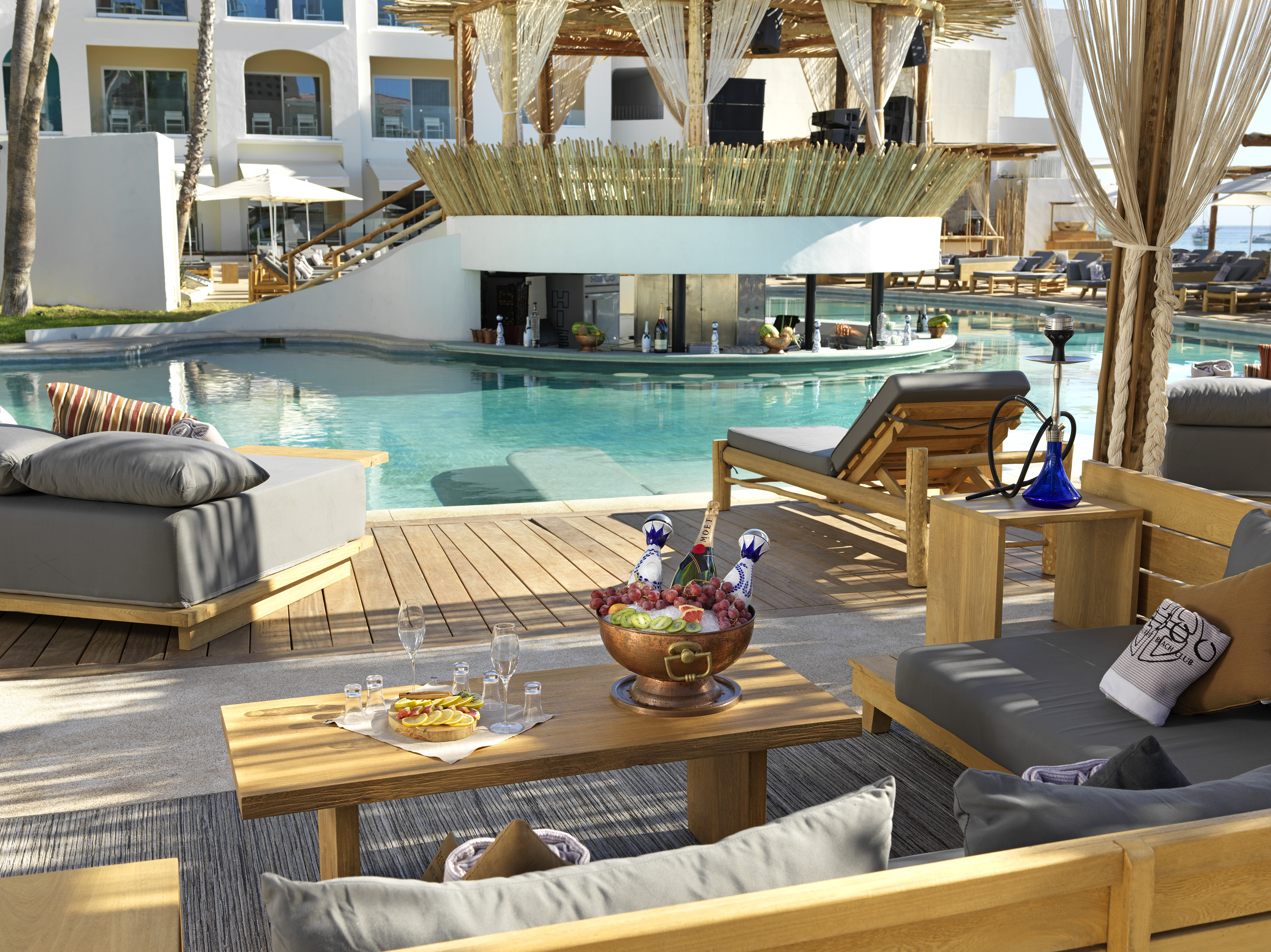 Tropical resort pool, swim-up bar, daybeds, and champagne on deck.