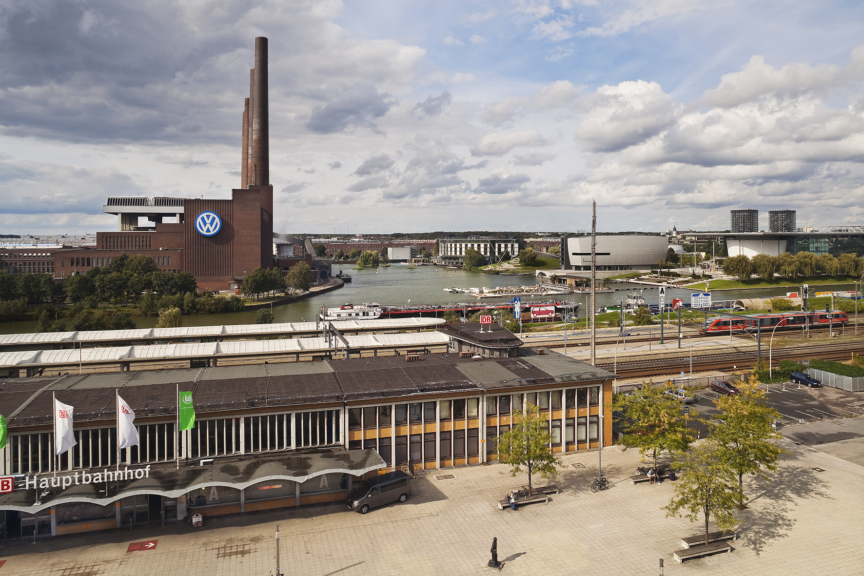 Wolfsburg Autostadt: Volkswagen factory, train station, canal, and modern buildings.
