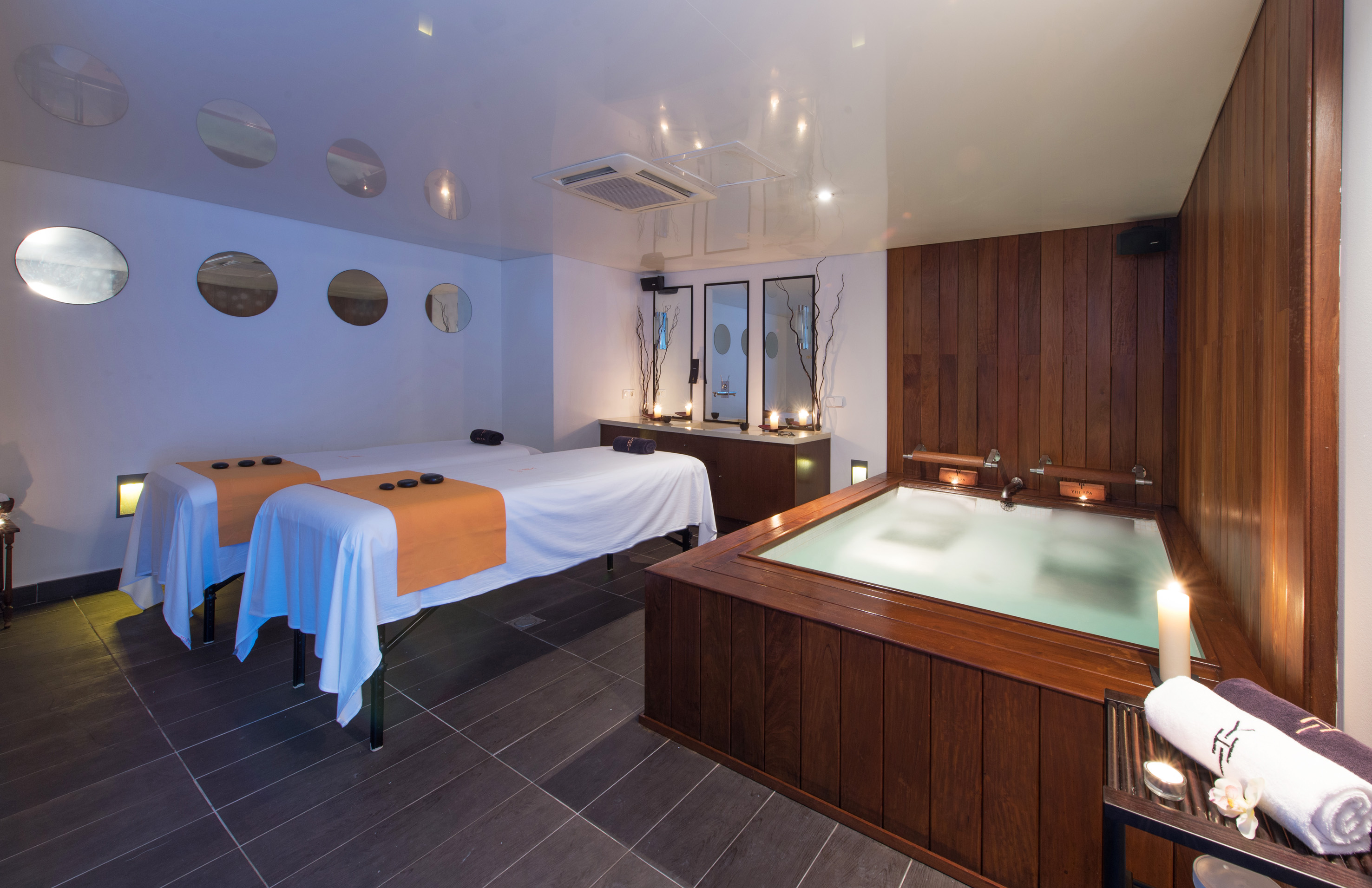Wellness spa room with two massage tables, hot stones, wooden hot tub.