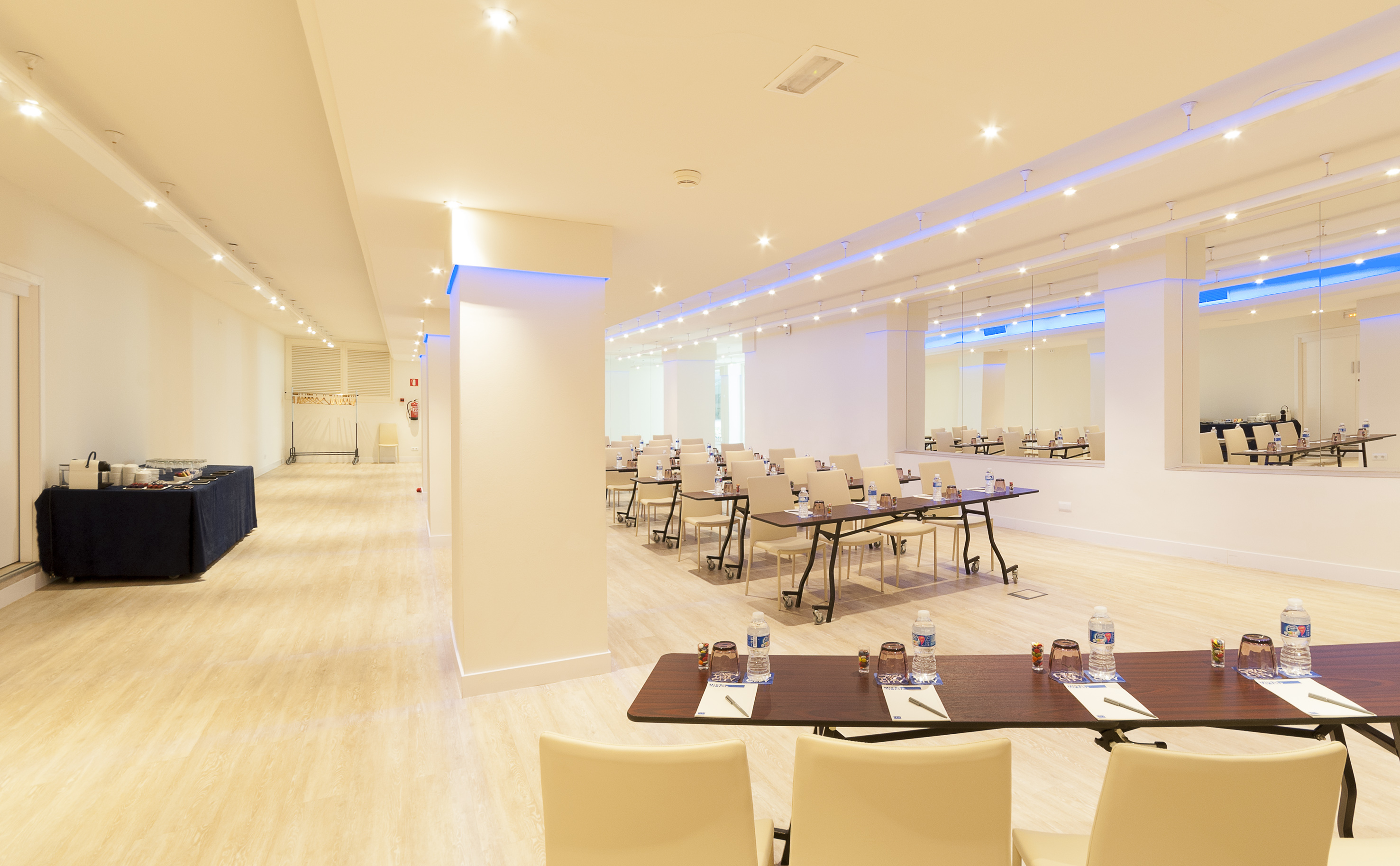 Modern meeting room with tables, chairs, and a refreshment buffet.