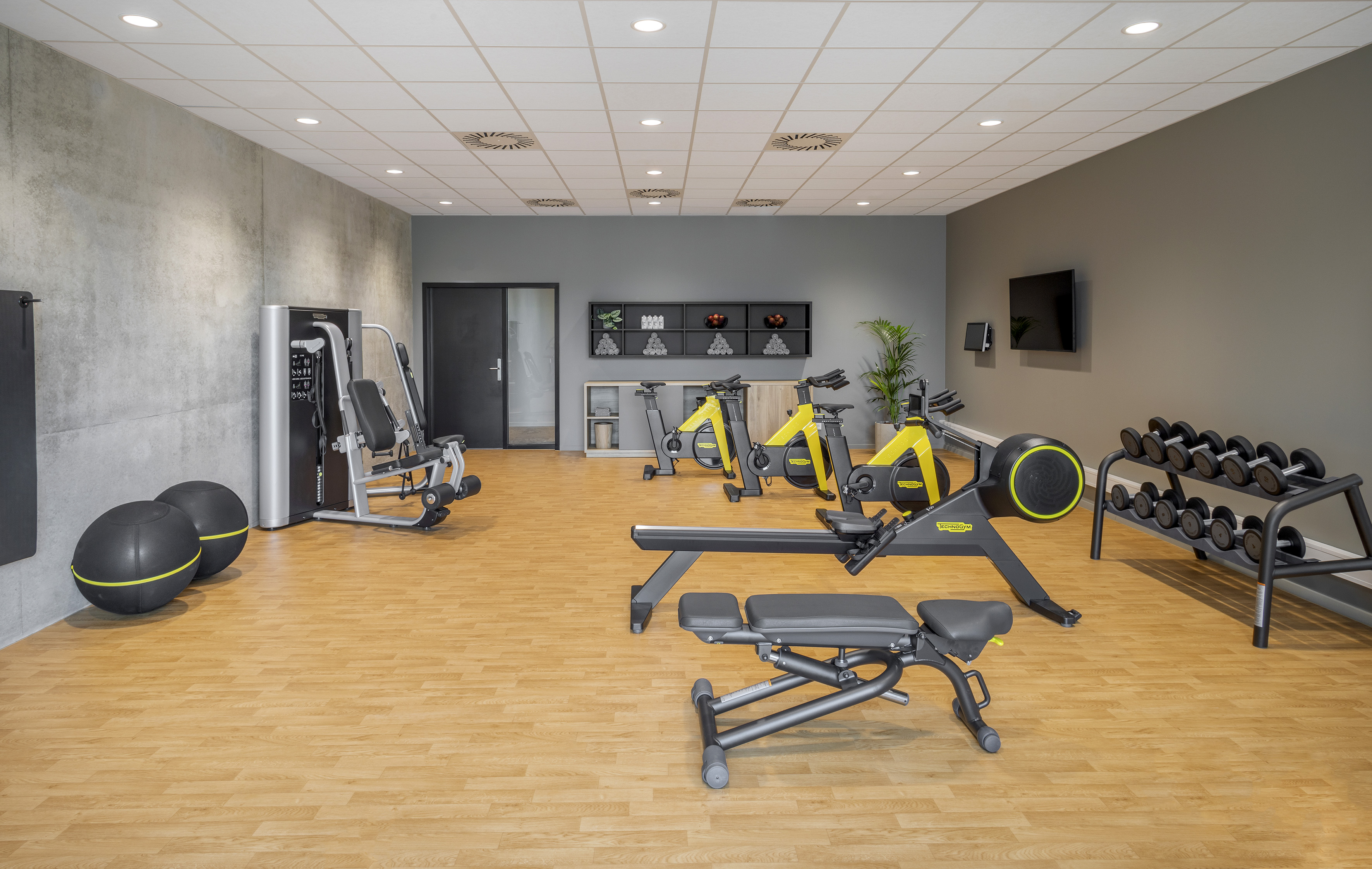 Fitness room with bikes, rowing machine, free weights, and strength equipment.