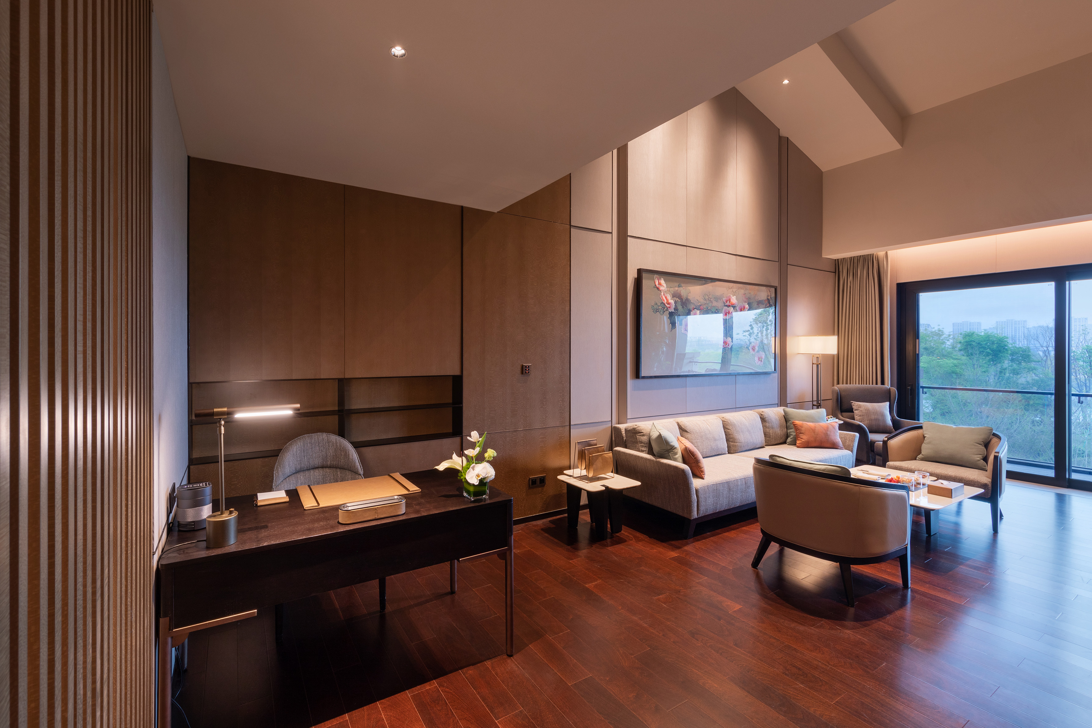 Contemporary hotel suite: living room, desk, wood floor, and scenic view.