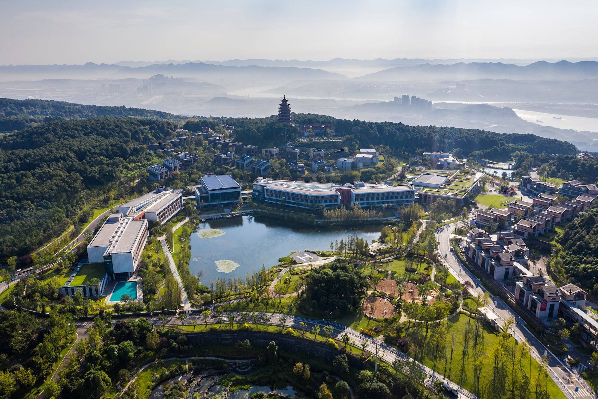Aerial view of Melia resort with lake, pagoda, and misty mountains.
