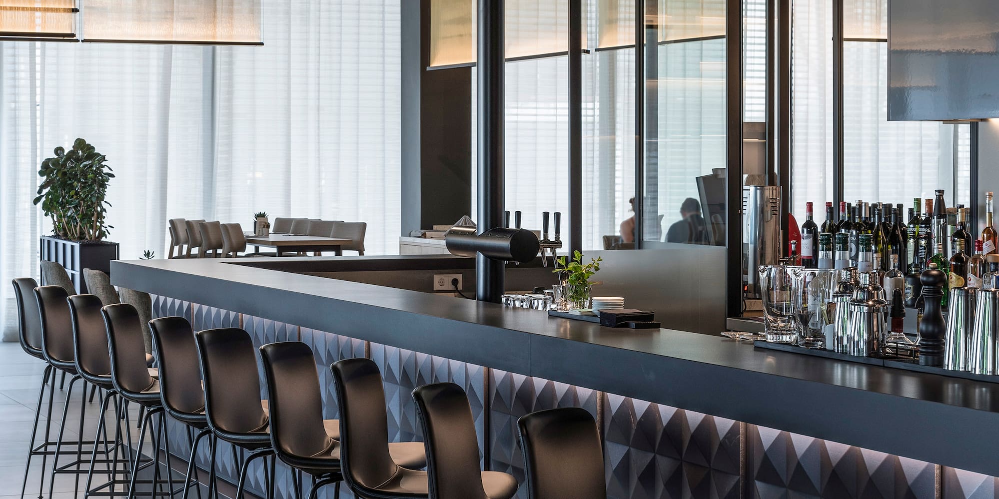 a bar with chairs and a row of bottles