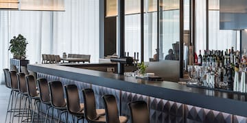 a bar with chairs and a row of bottles