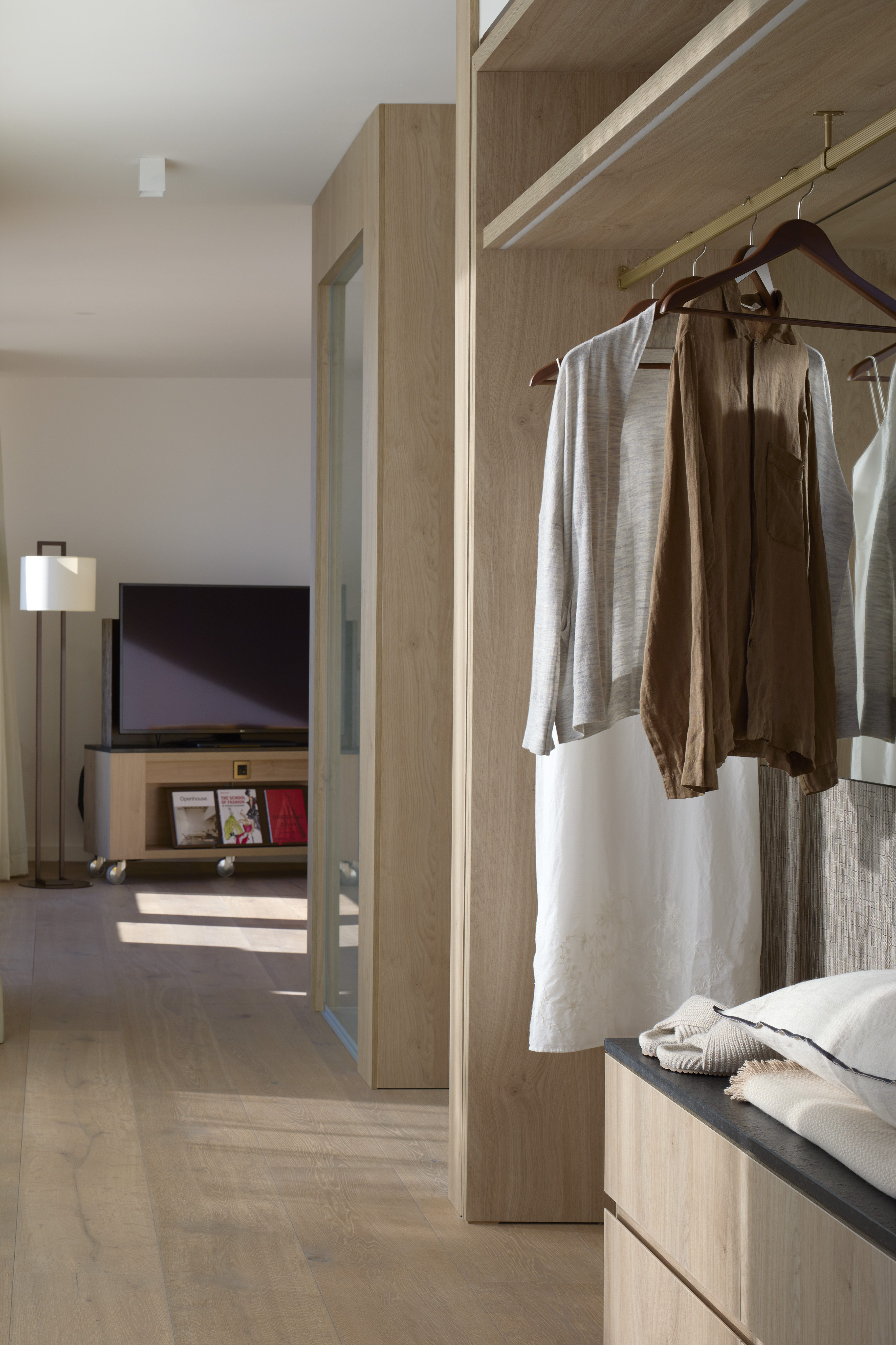 Light wood open wardrobe with hanging clothes, modern minimalist bedroom design.
