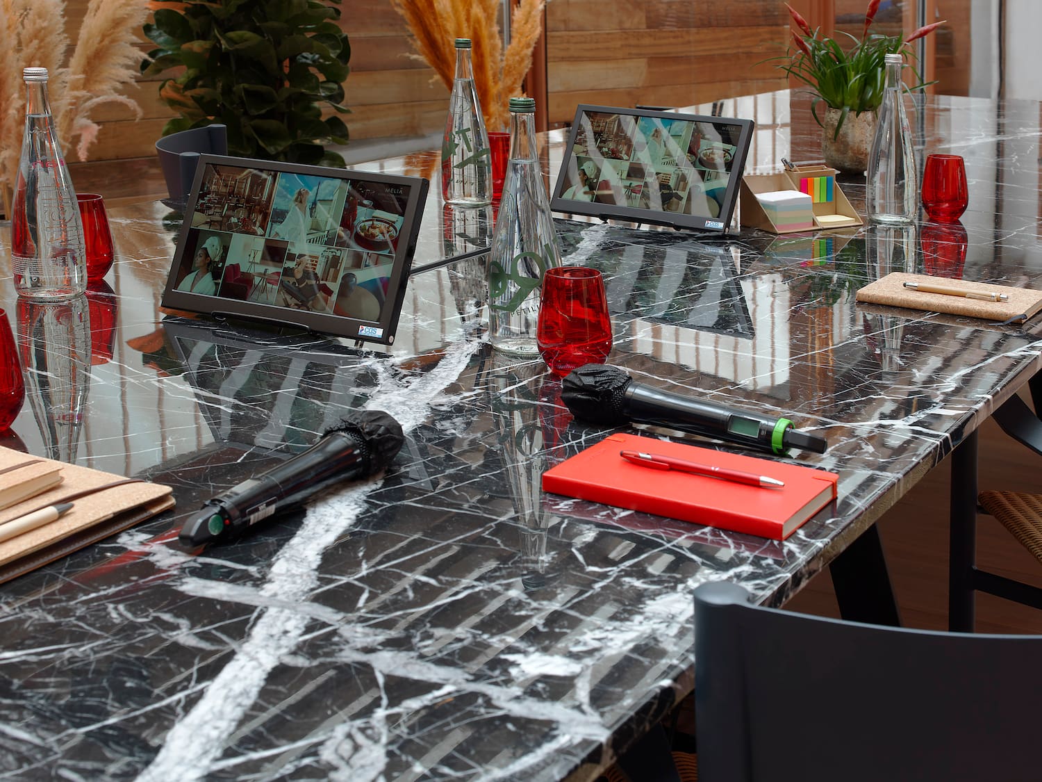 Black marble conference table with dual screens, microphones, and glass water.