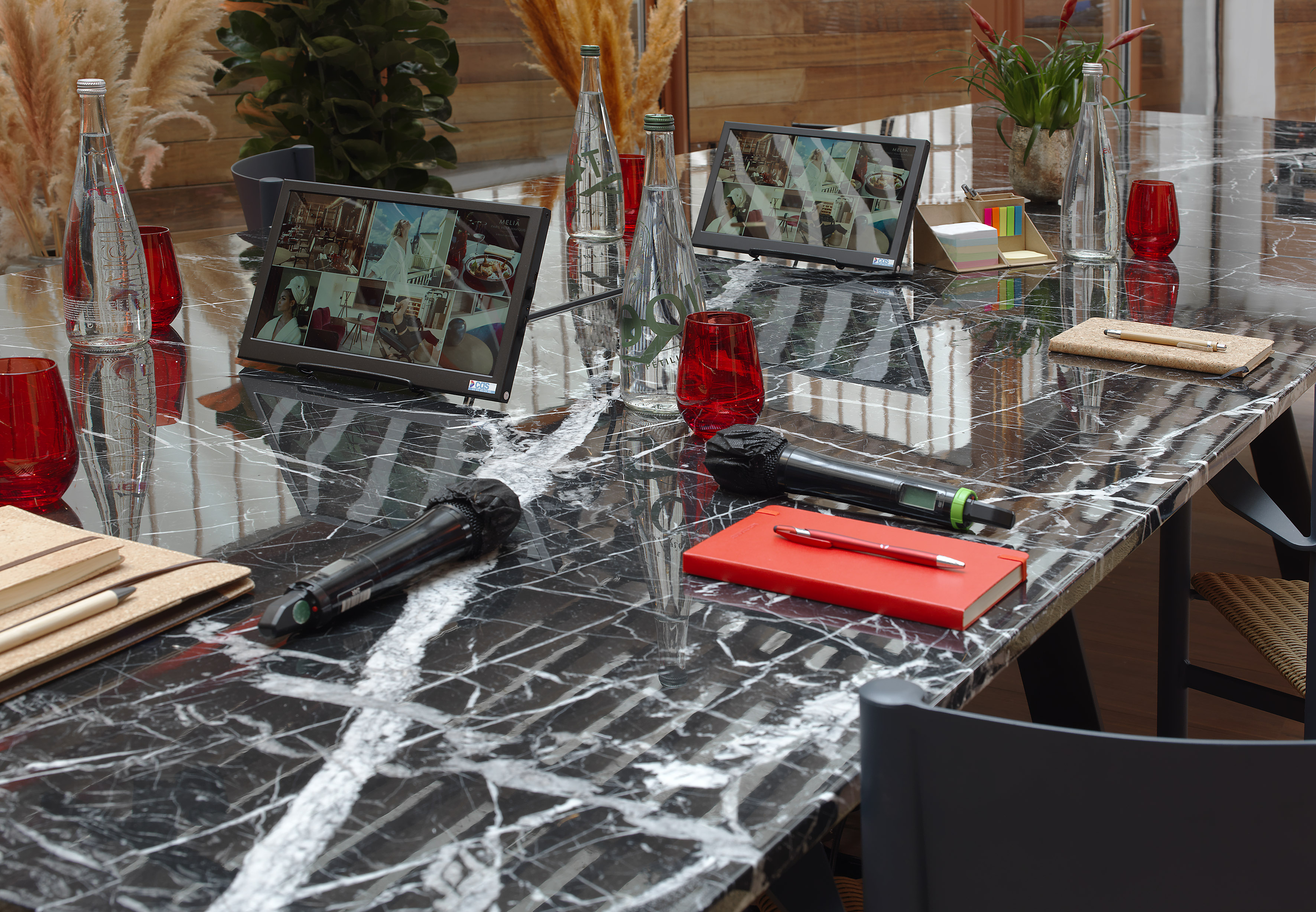 Black marble conference table with dual screens, microphones, and glass water.