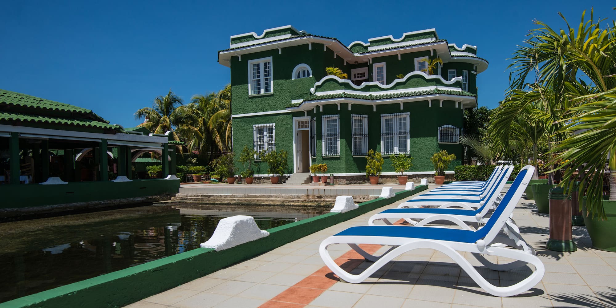 a green house with a pool and lounge chairs