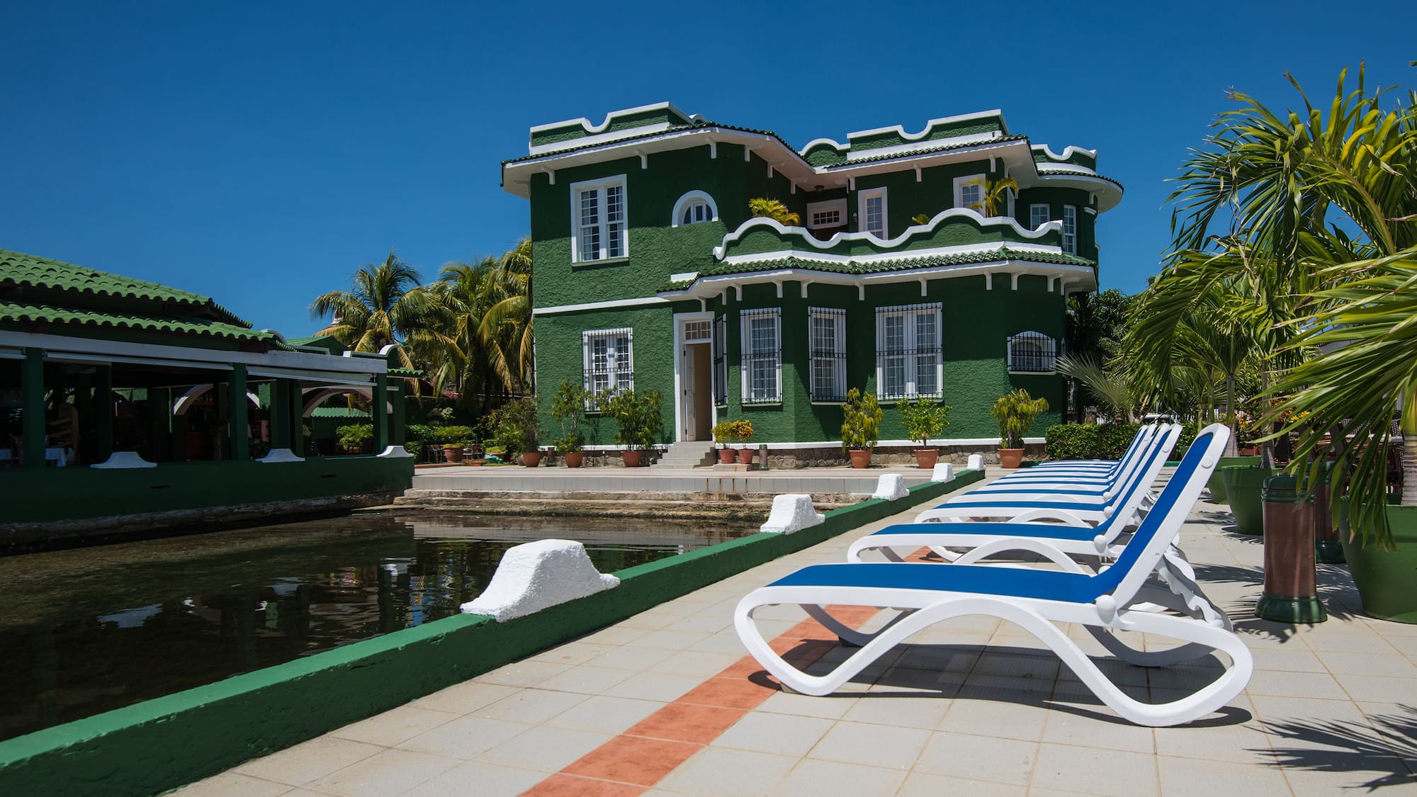 a green house with a pool and lounge chairs