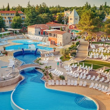 a swimming pool with chairs and a pool in a resort