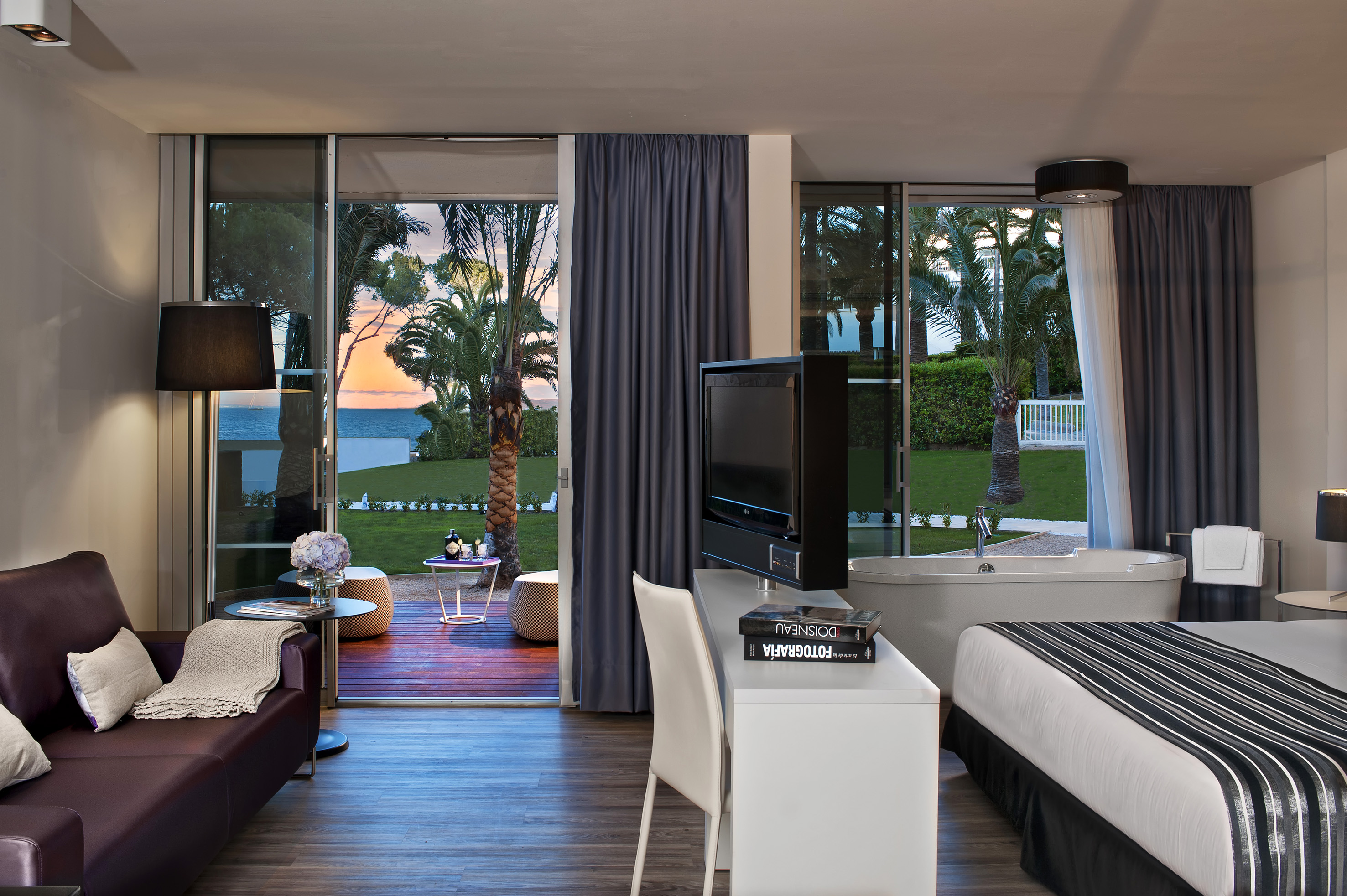 Luxury hotel suite with private terrace, sea view, modern decor, and palm trees.