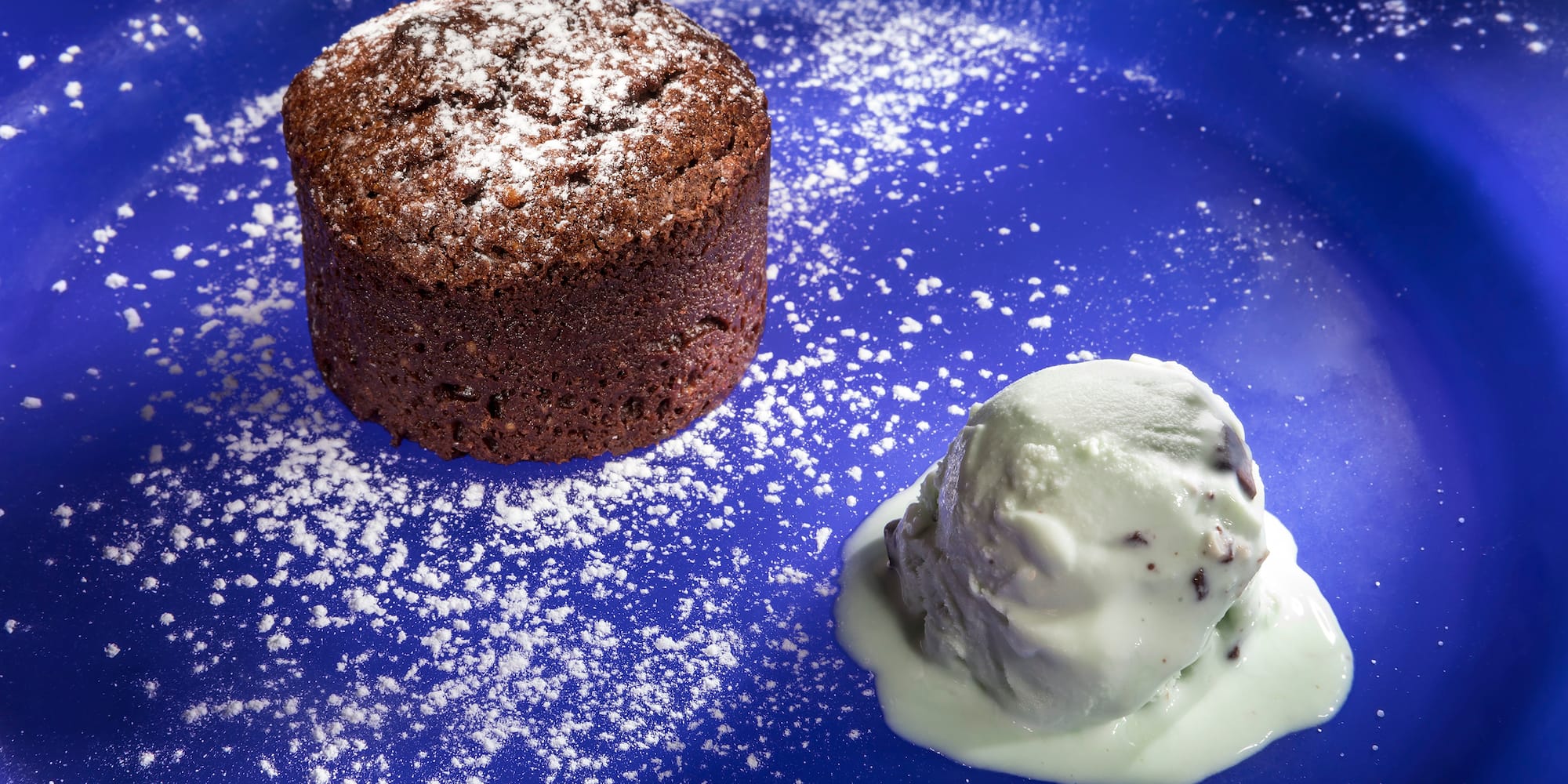 a chocolate cake with a scoop of ice cream on a blue plate