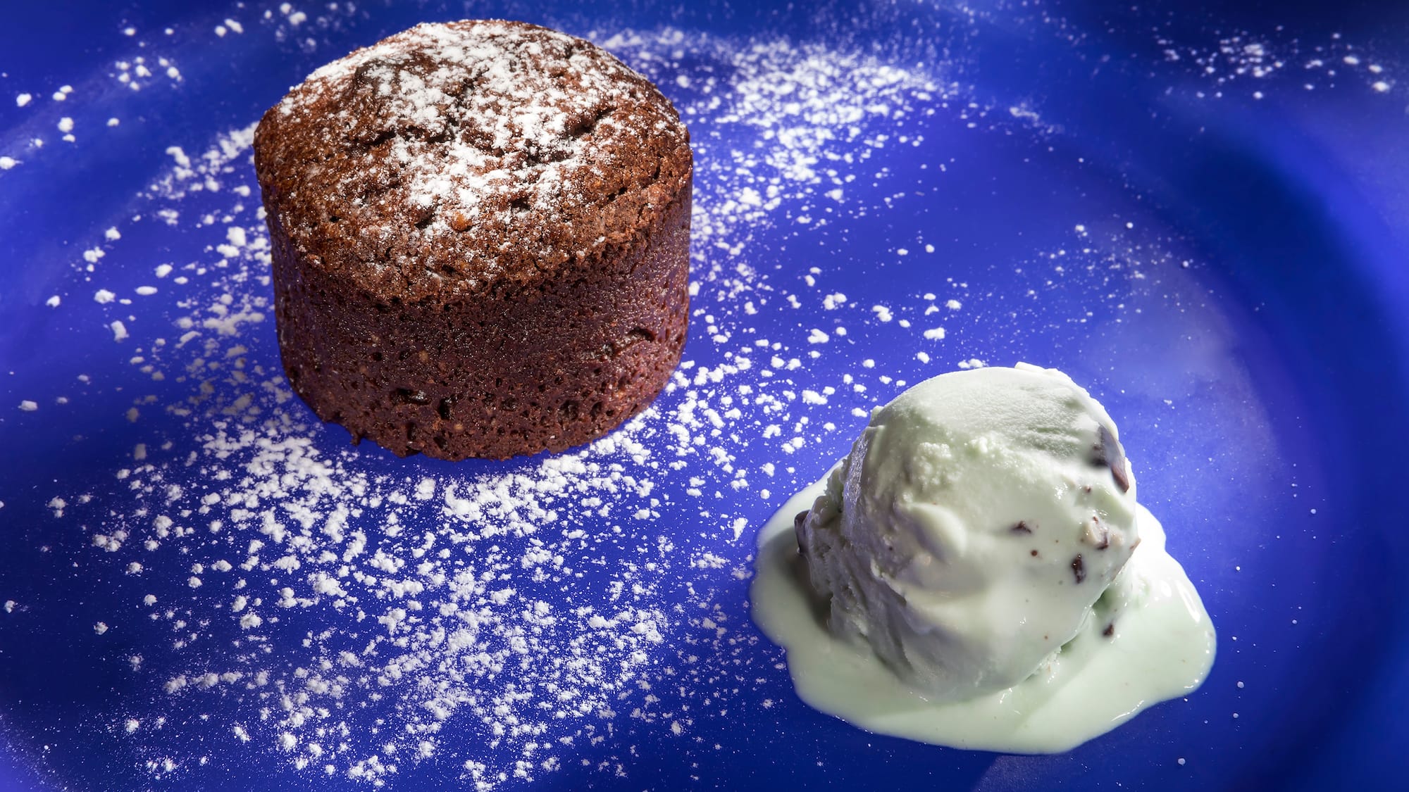 a chocolate cake with a scoop of ice cream on a blue plate