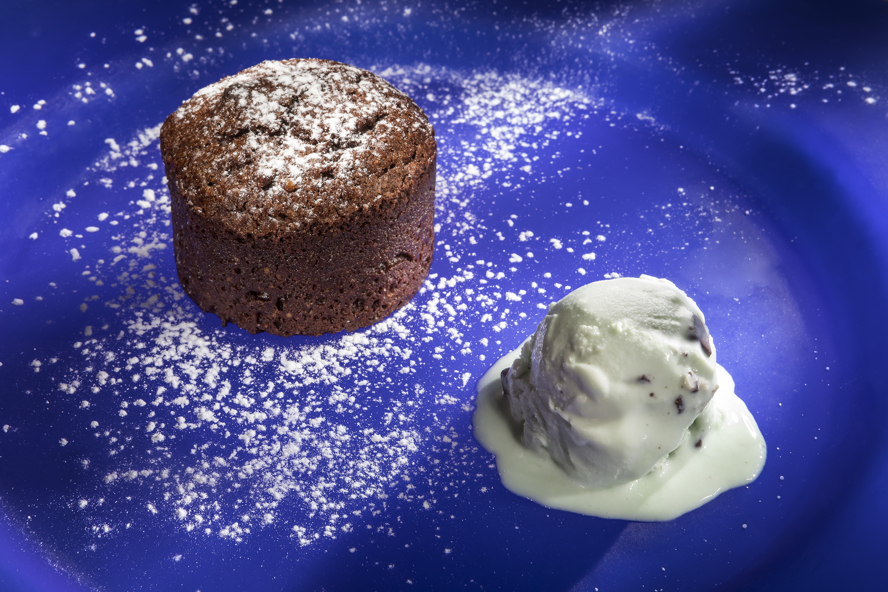 Dark chocolate cake with powdered sugar and mint chip ice cream.