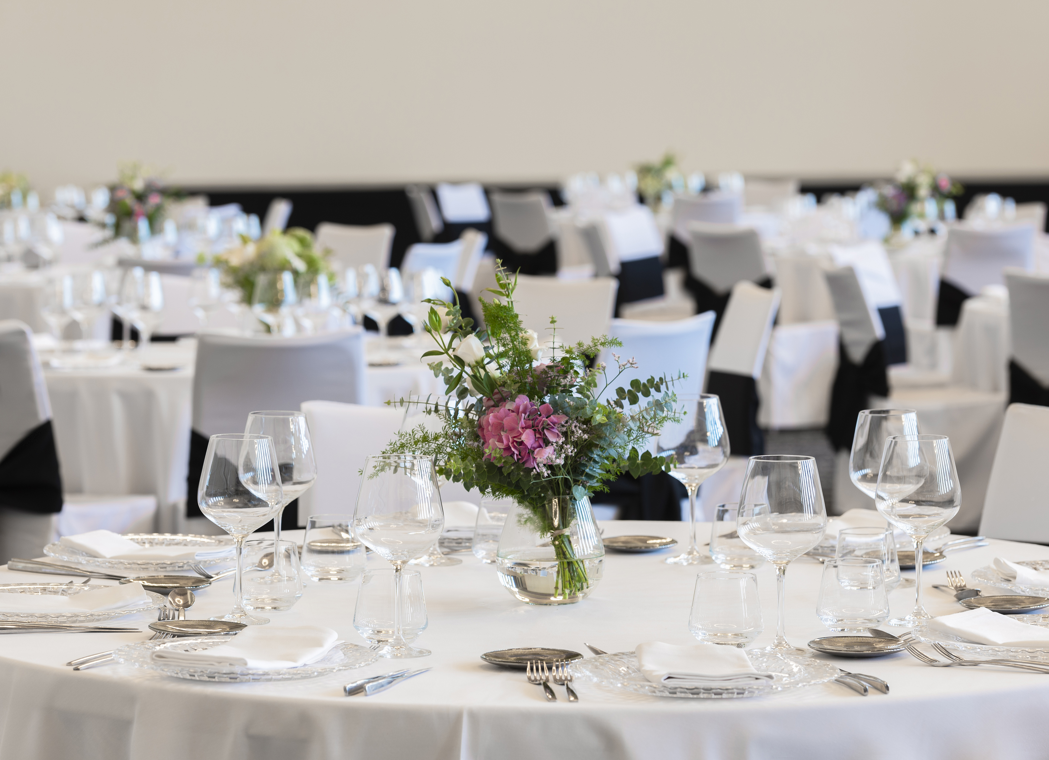 Banquet table with formal place settings and pink floral centerpiece.